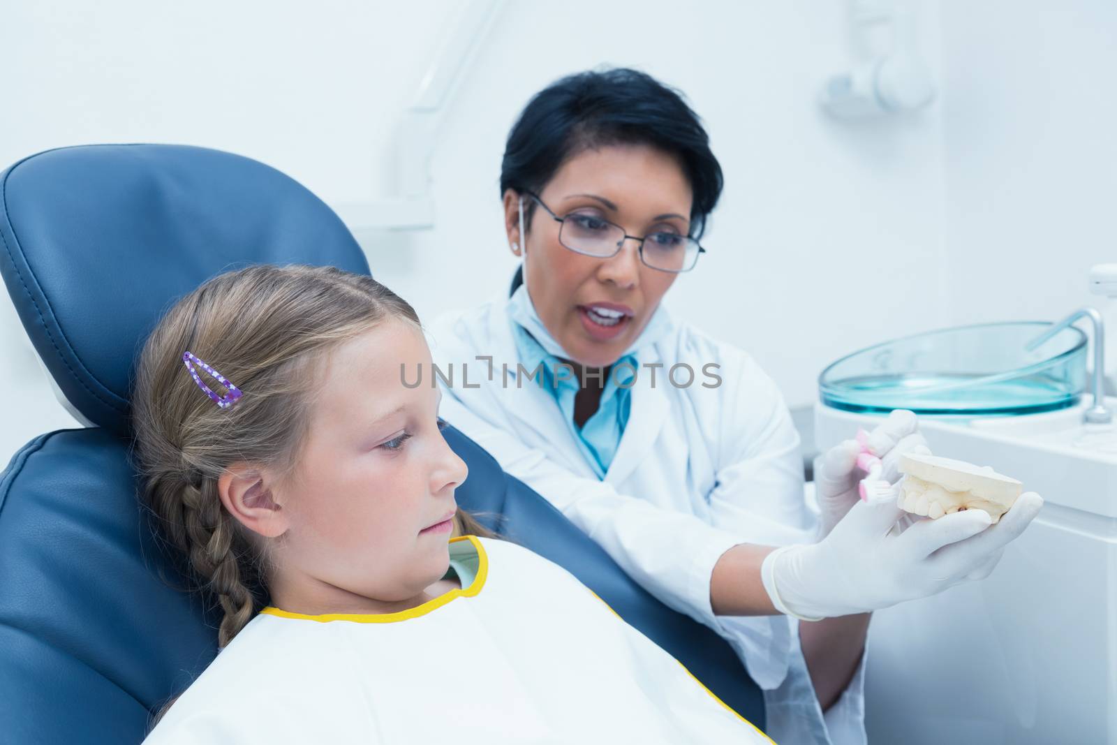 Dentist teaching girl how to brush teeth by Wavebreakmedia