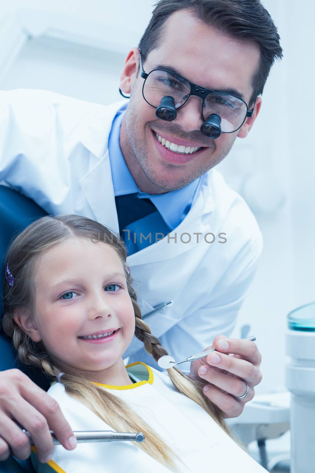 Male dentist examining girls teeth in the dentists chair