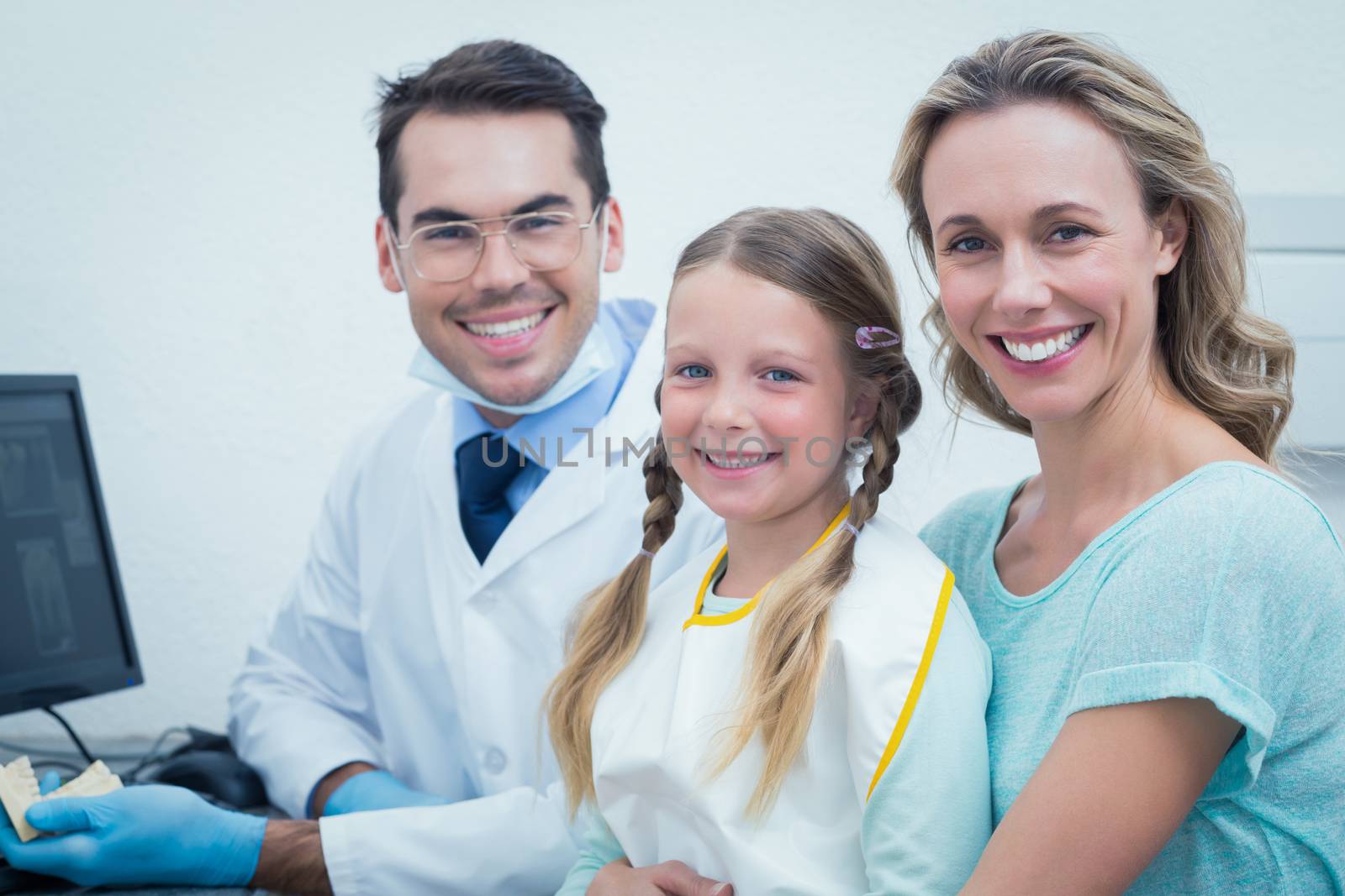 Portrait of happy male dentist with assistant and little girl