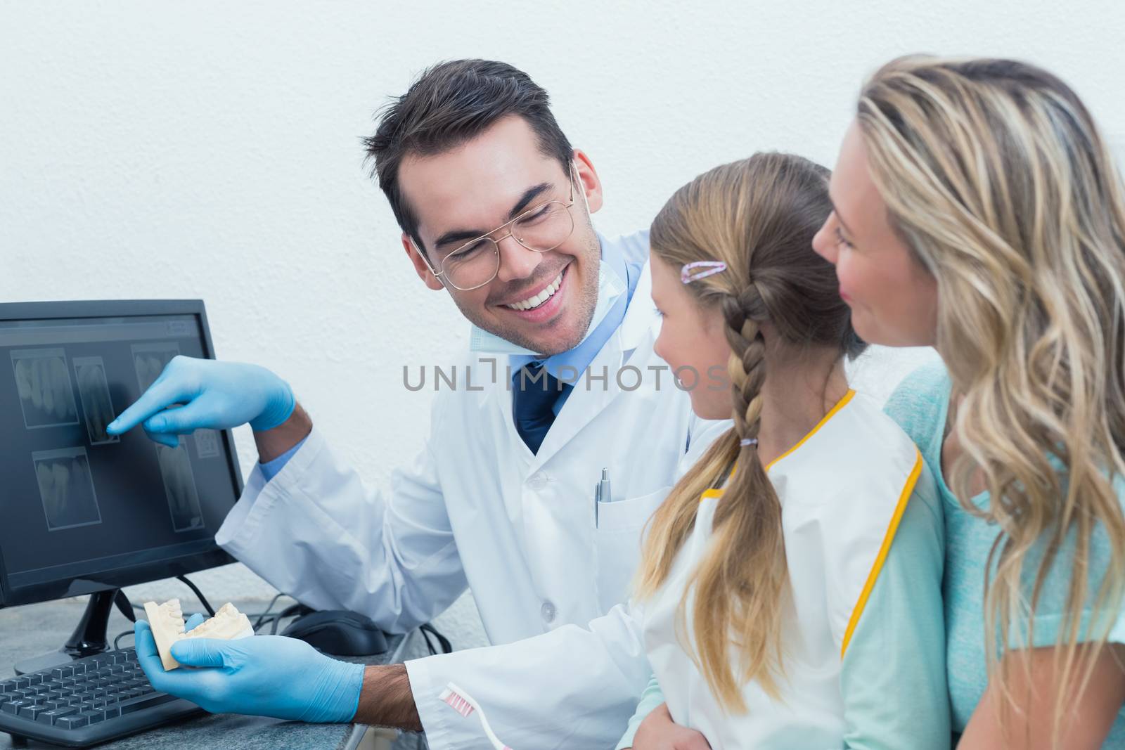 Dentist with assistant showing little girl her mouth x-ray by Wavebreakmedia