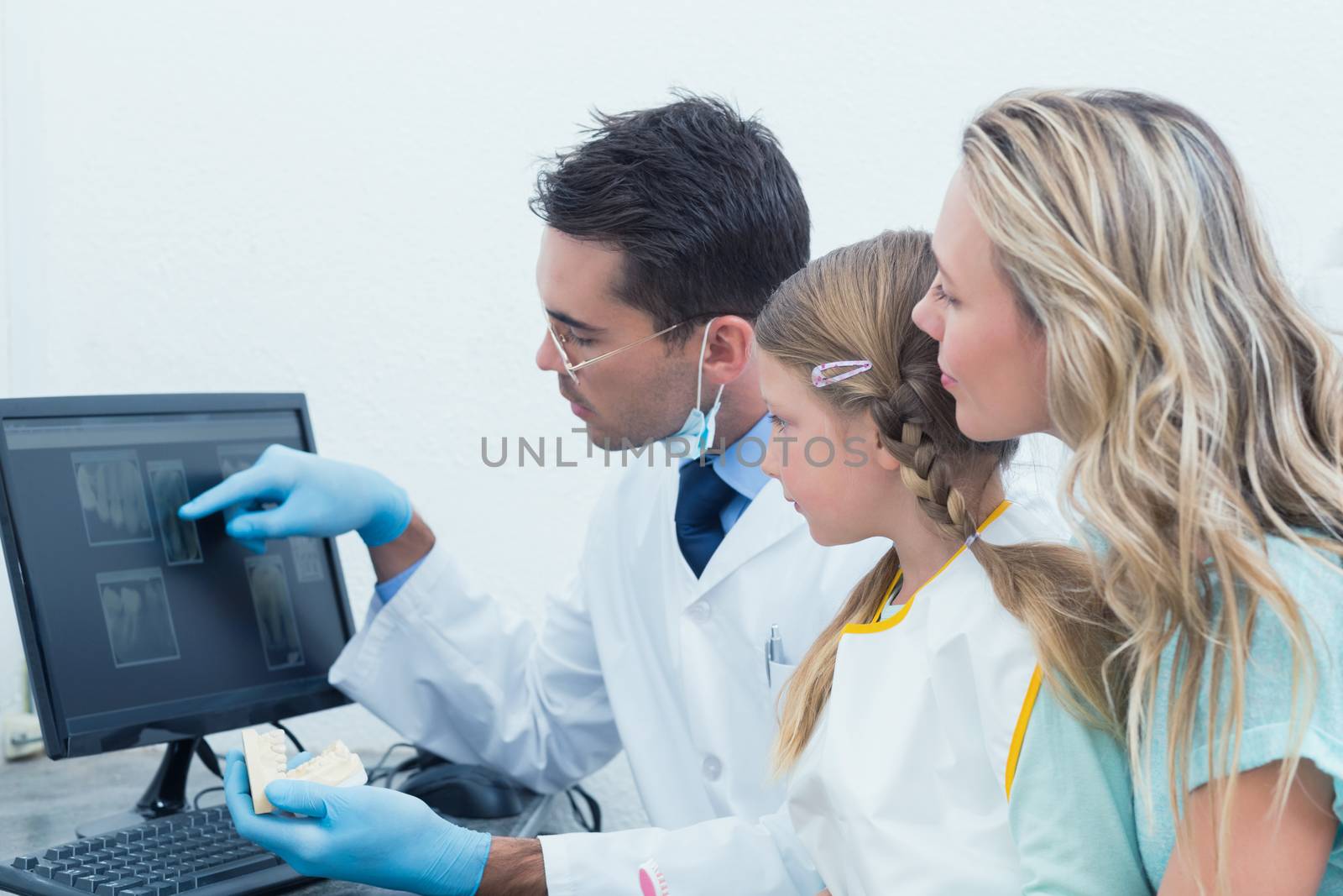 Dentist and assistant showing little girl her mouth x-ray by Wavebreakmedia