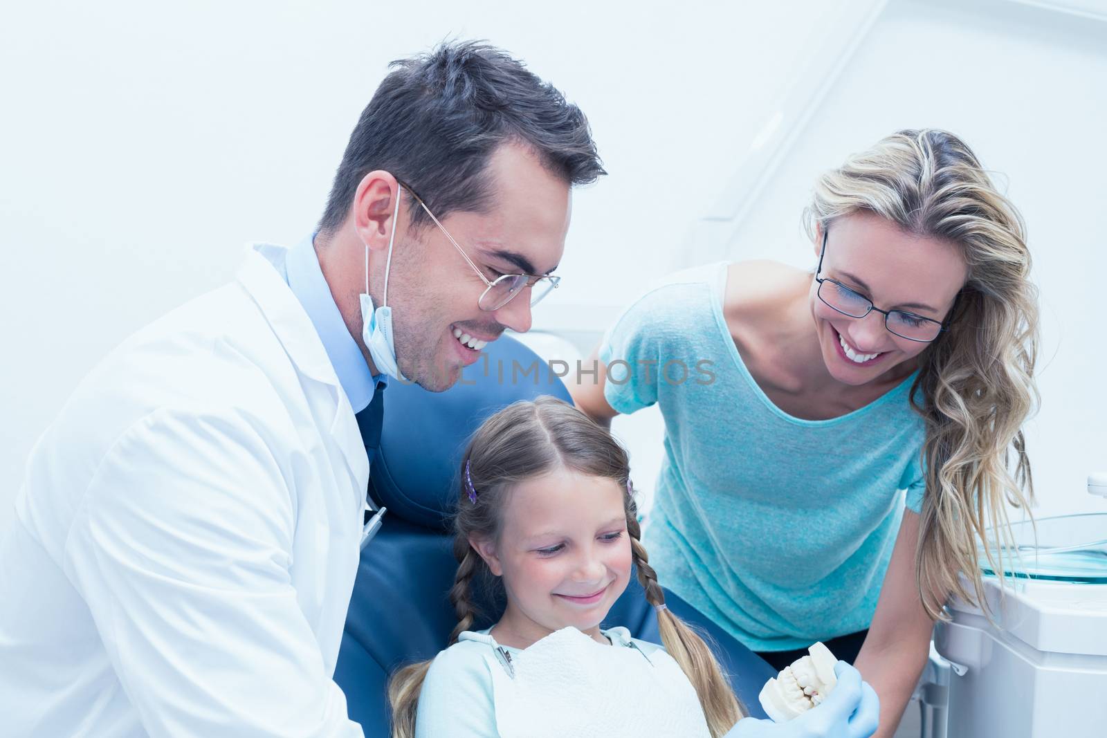Happy male dentist with assistant and girl by Wavebreakmedia