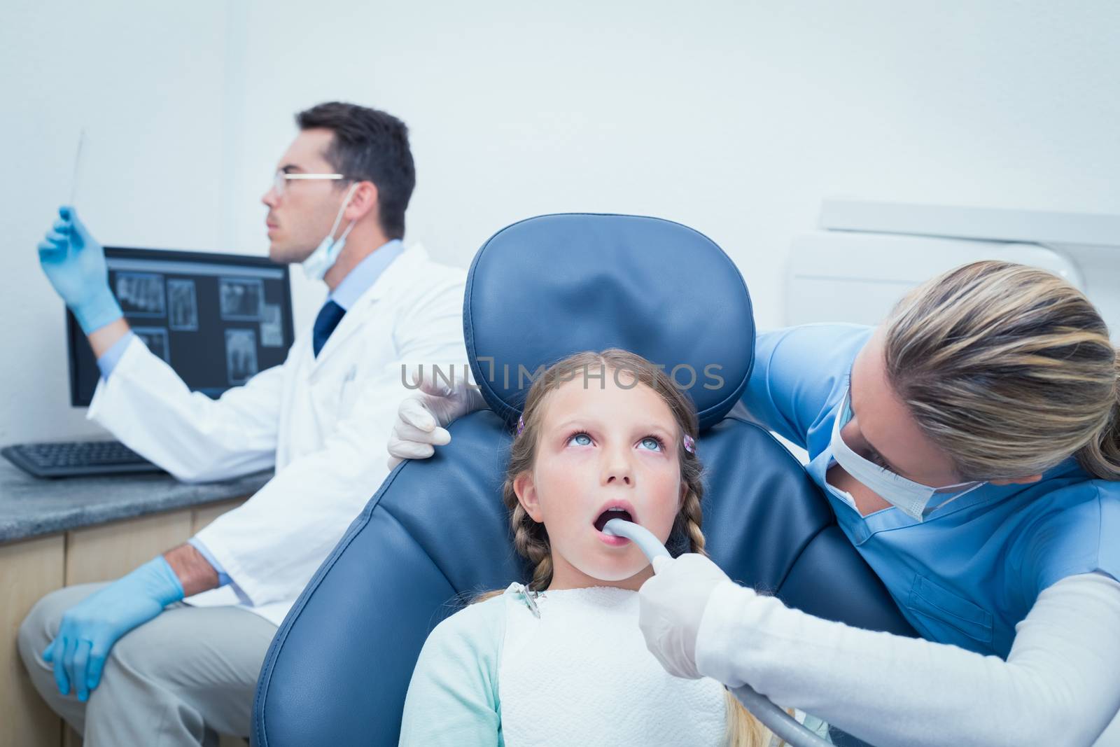 Female dentist examining girls teeth in the dentists chair