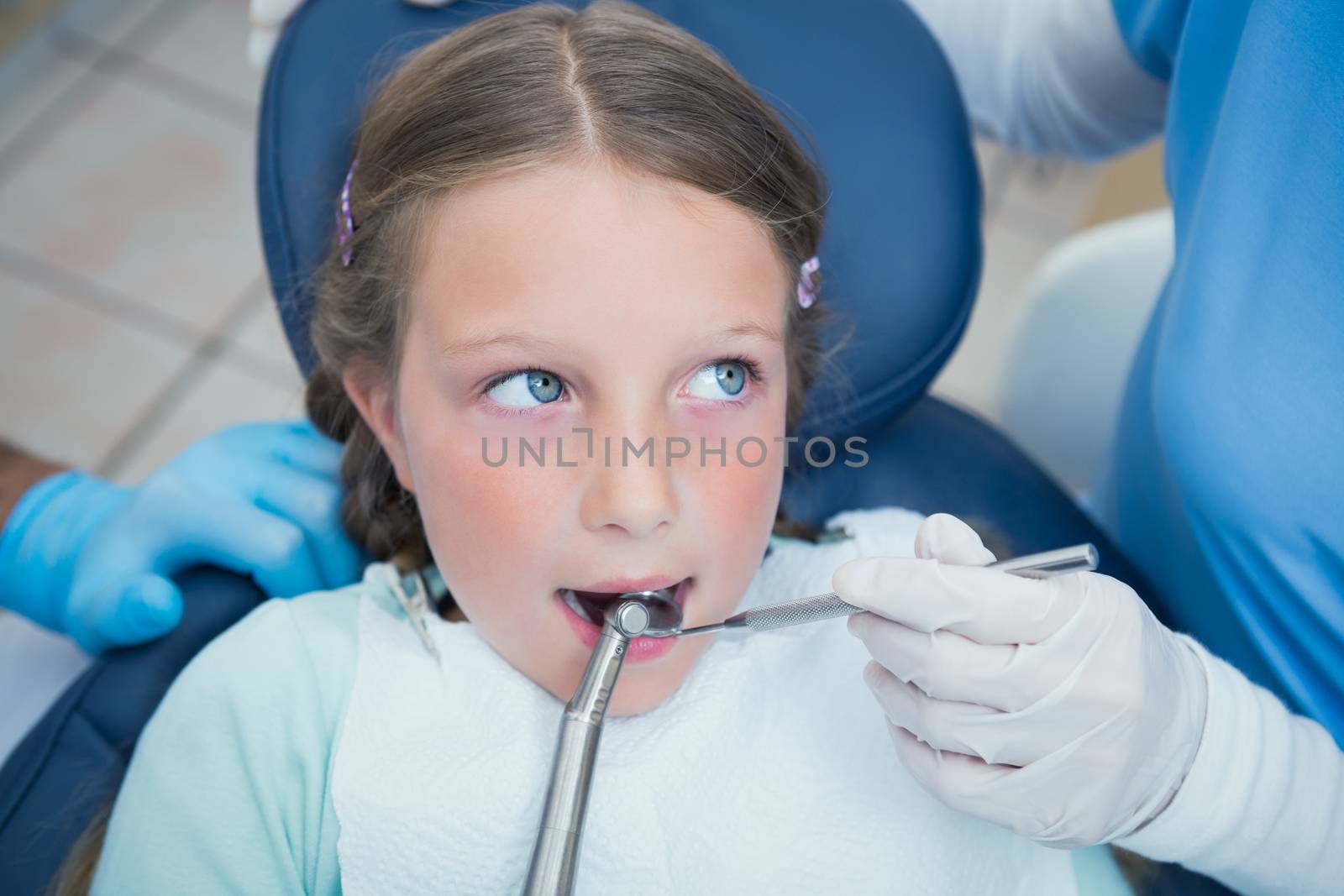 Dentist with assistant examining girls teeth by Wavebreakmedia