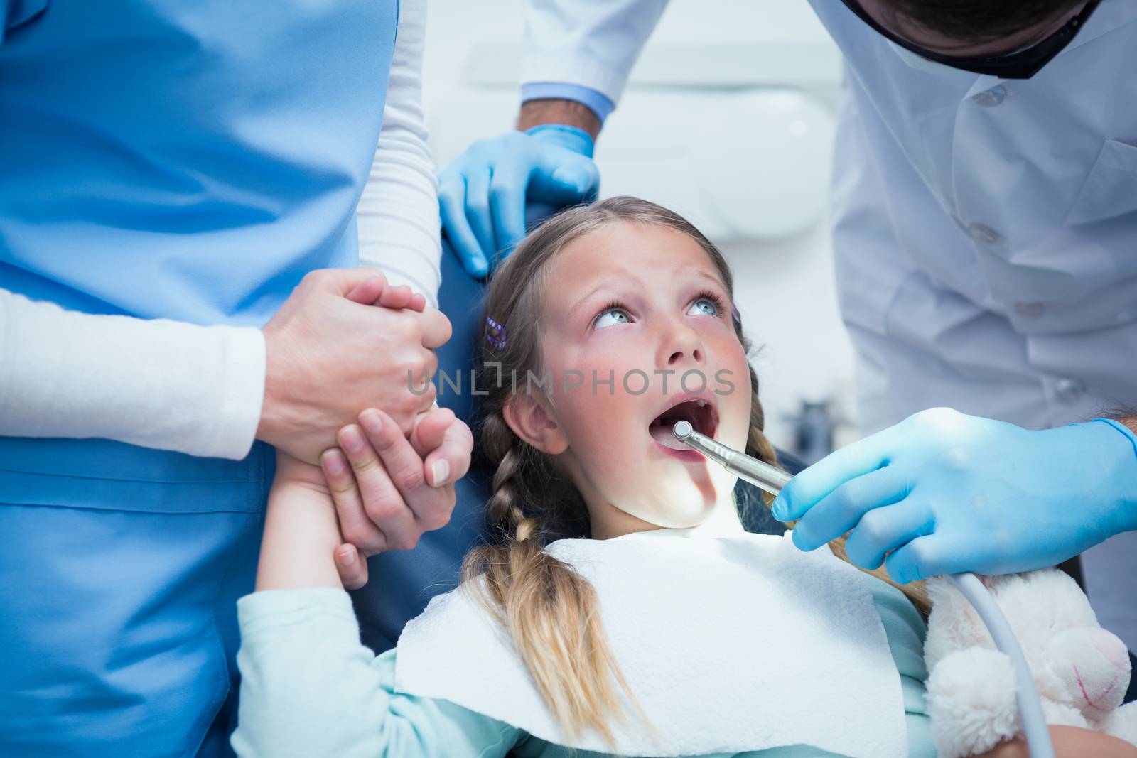 Dentist with assistant examining girls teeth in the dentists chair