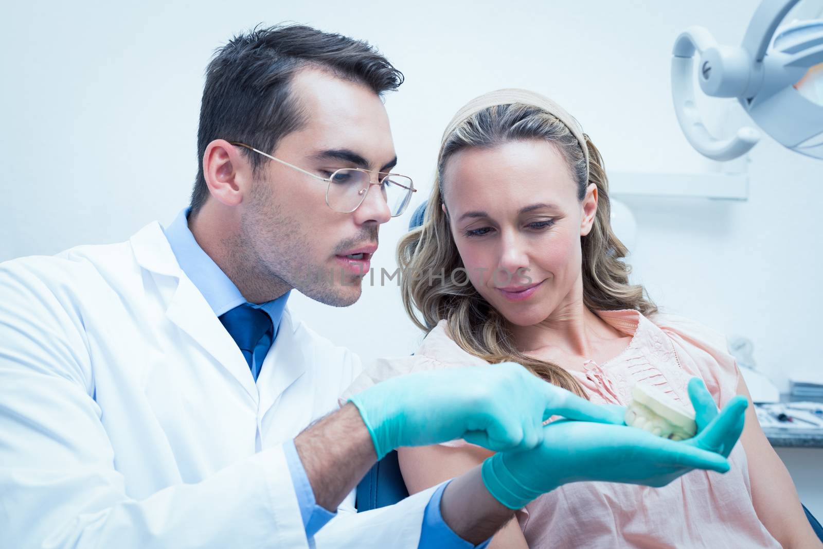 Male dentist showing woman prosthesis teeth by Wavebreakmedia