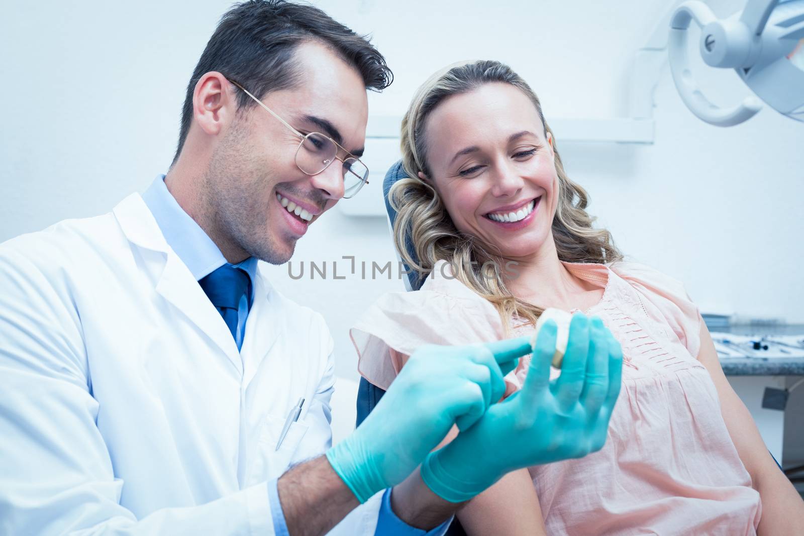 Male dentist teaching woman how to brush teeth in the dentists chair