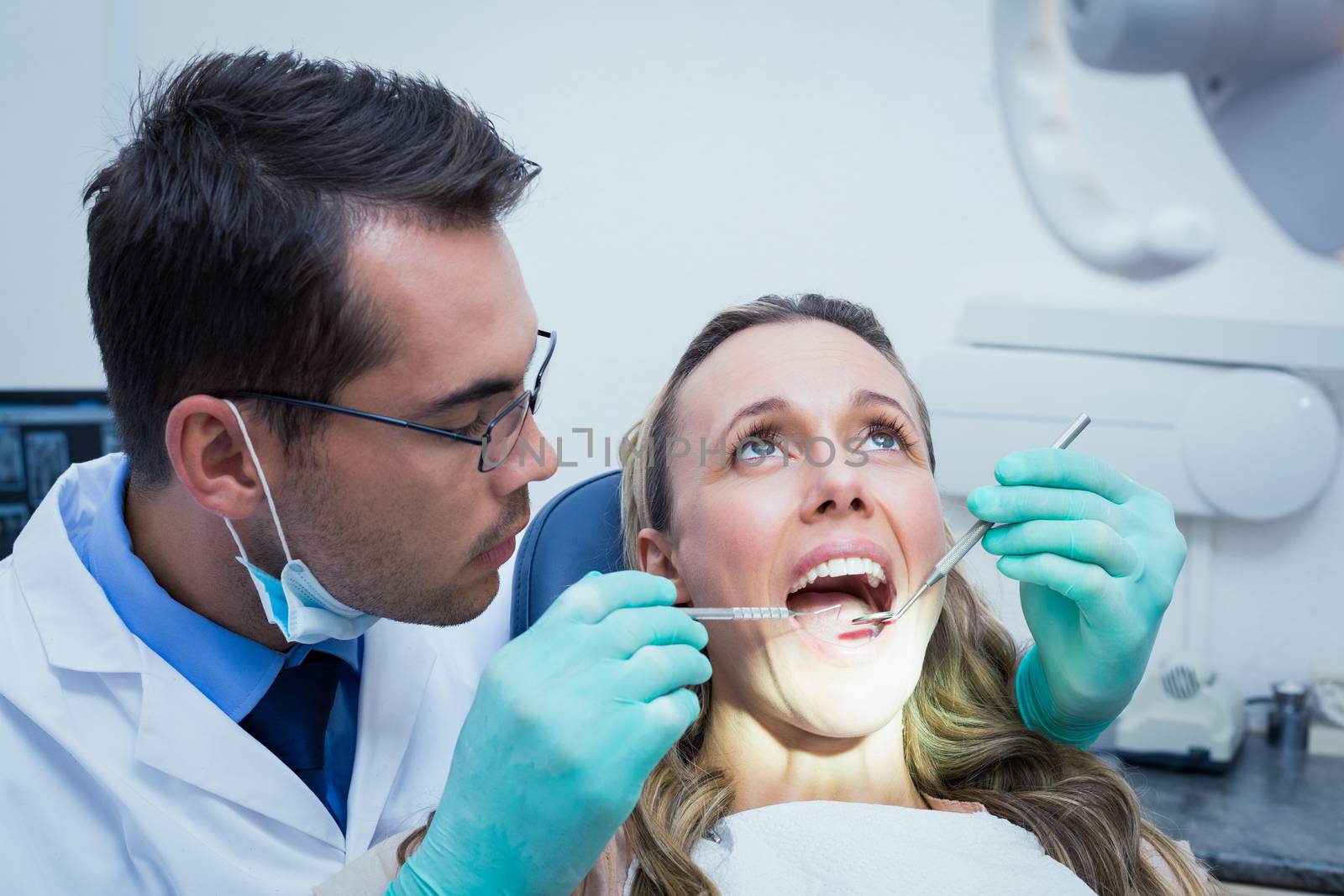 Dentist examining young womans teeth in the dentists chair