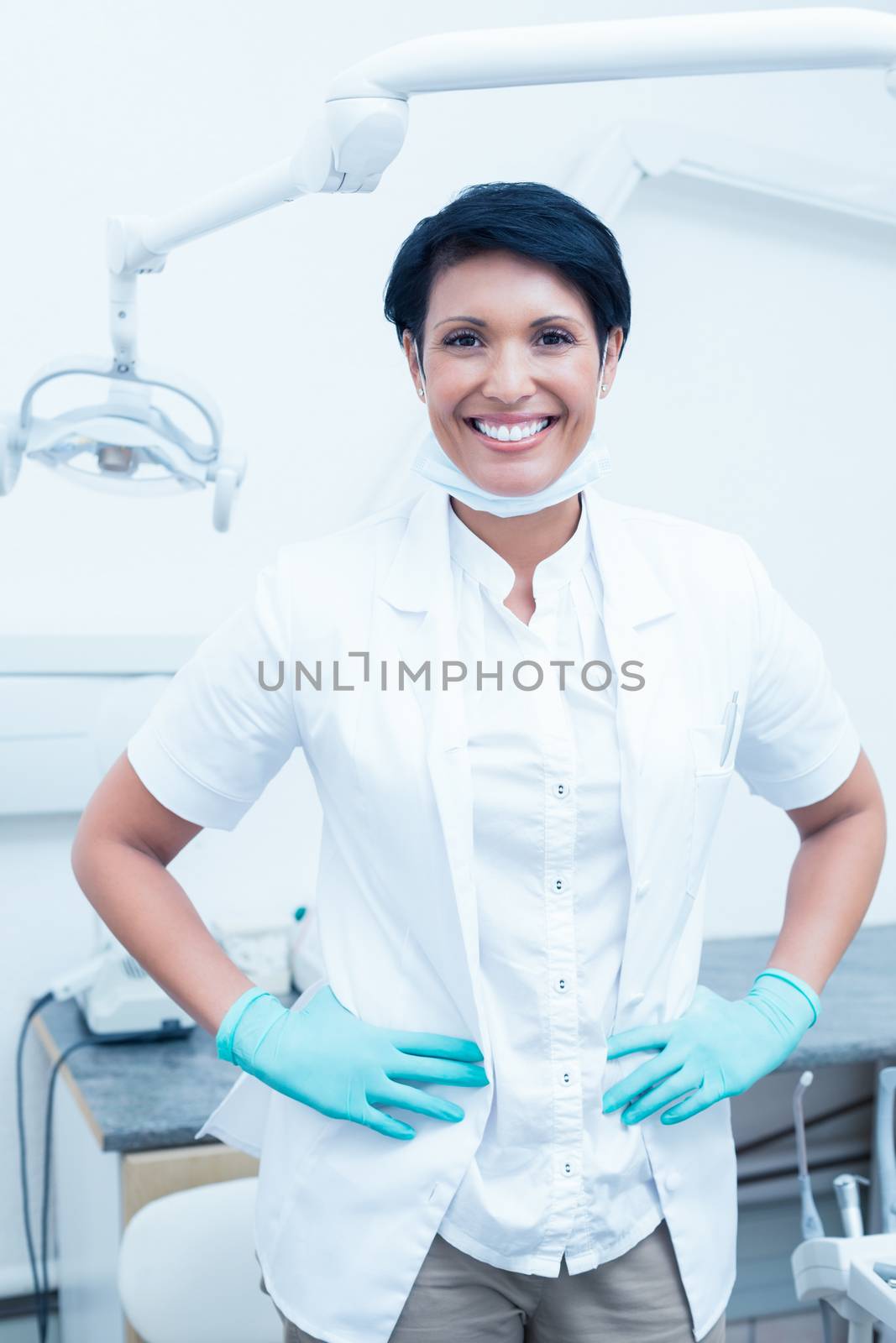 Portrait of happy confident female dentist with hands on hips
