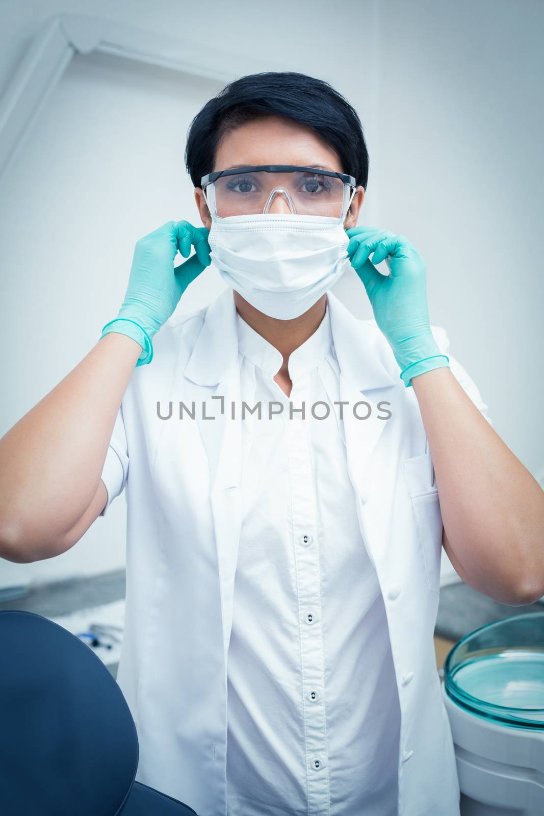 Dentist wearing surgical mask and safety glasses by Wavebreakmedia