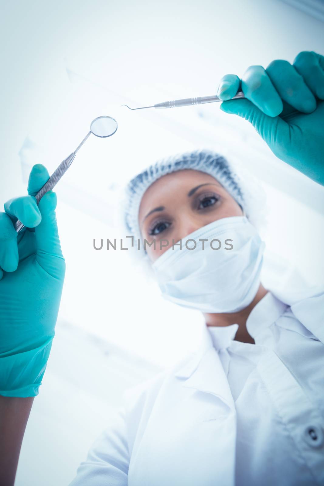 Female dentist in surgical mask holding dental tools by Wavebreakmedia