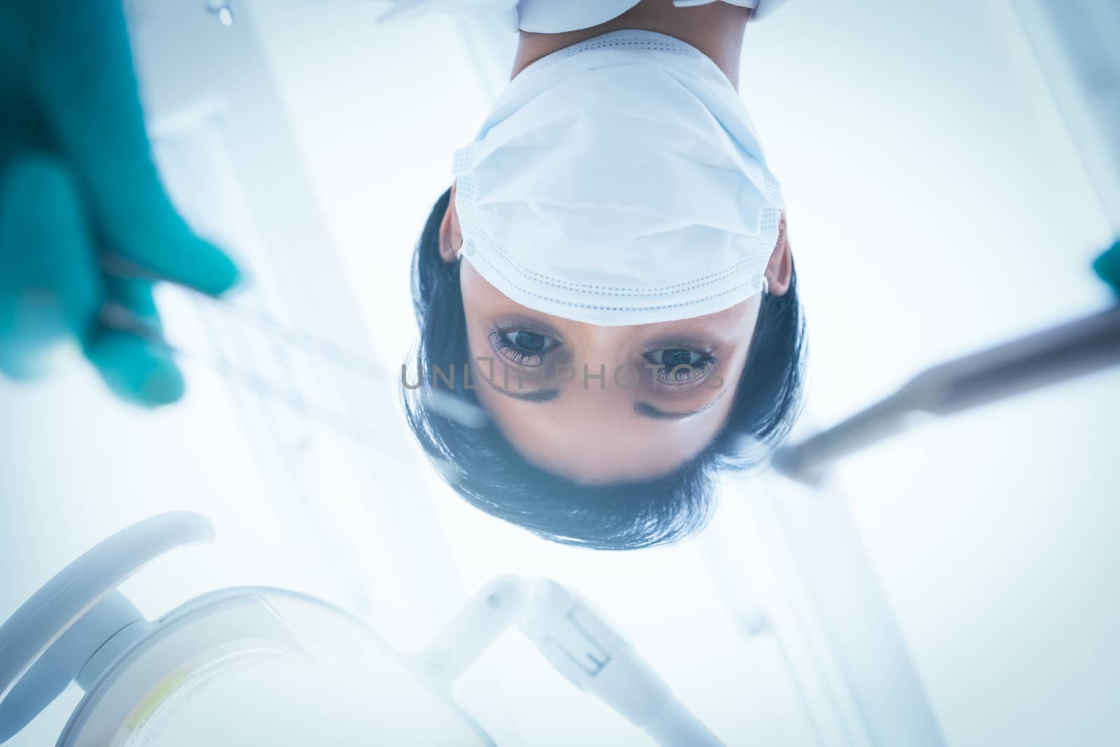 Low angle view of female dentist in surgical mask holding dental tools