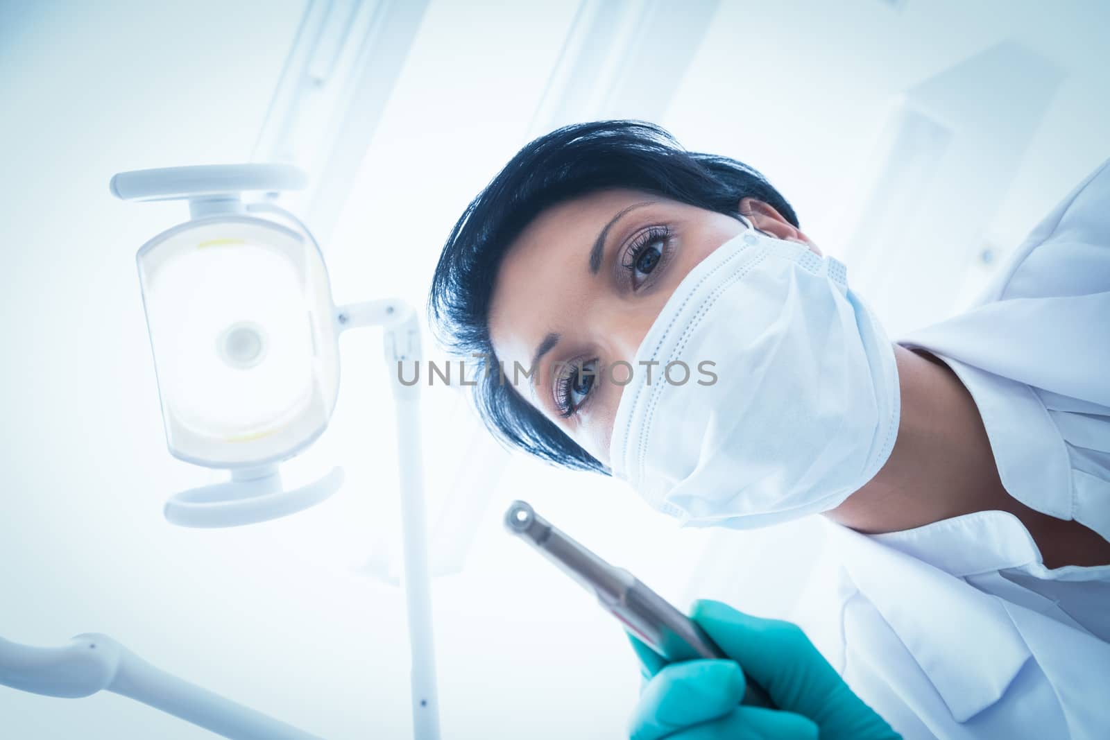 Portrait of female dentist in surgical mask holding dental drill