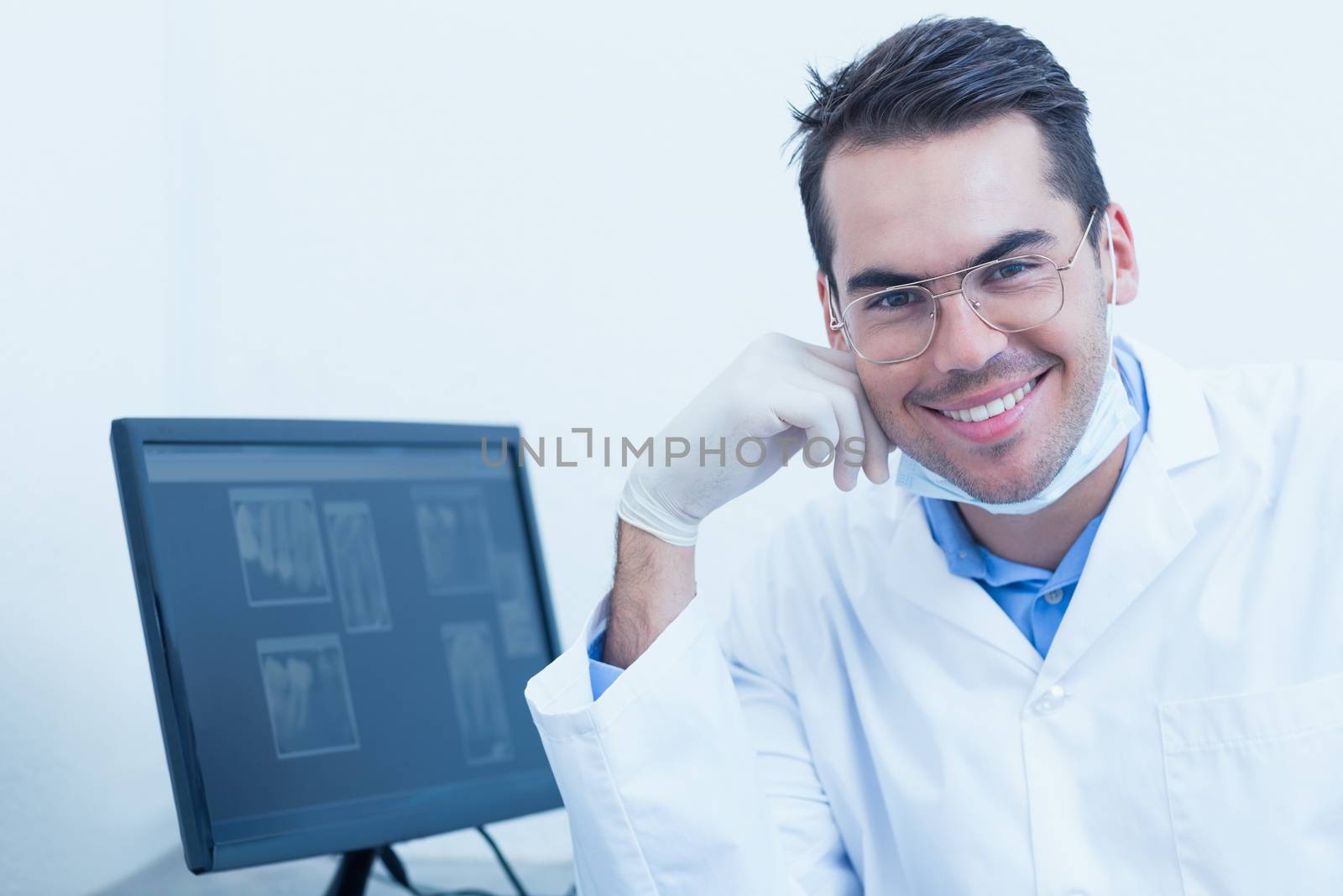 Portrait of smiling male dentist with computer monitor