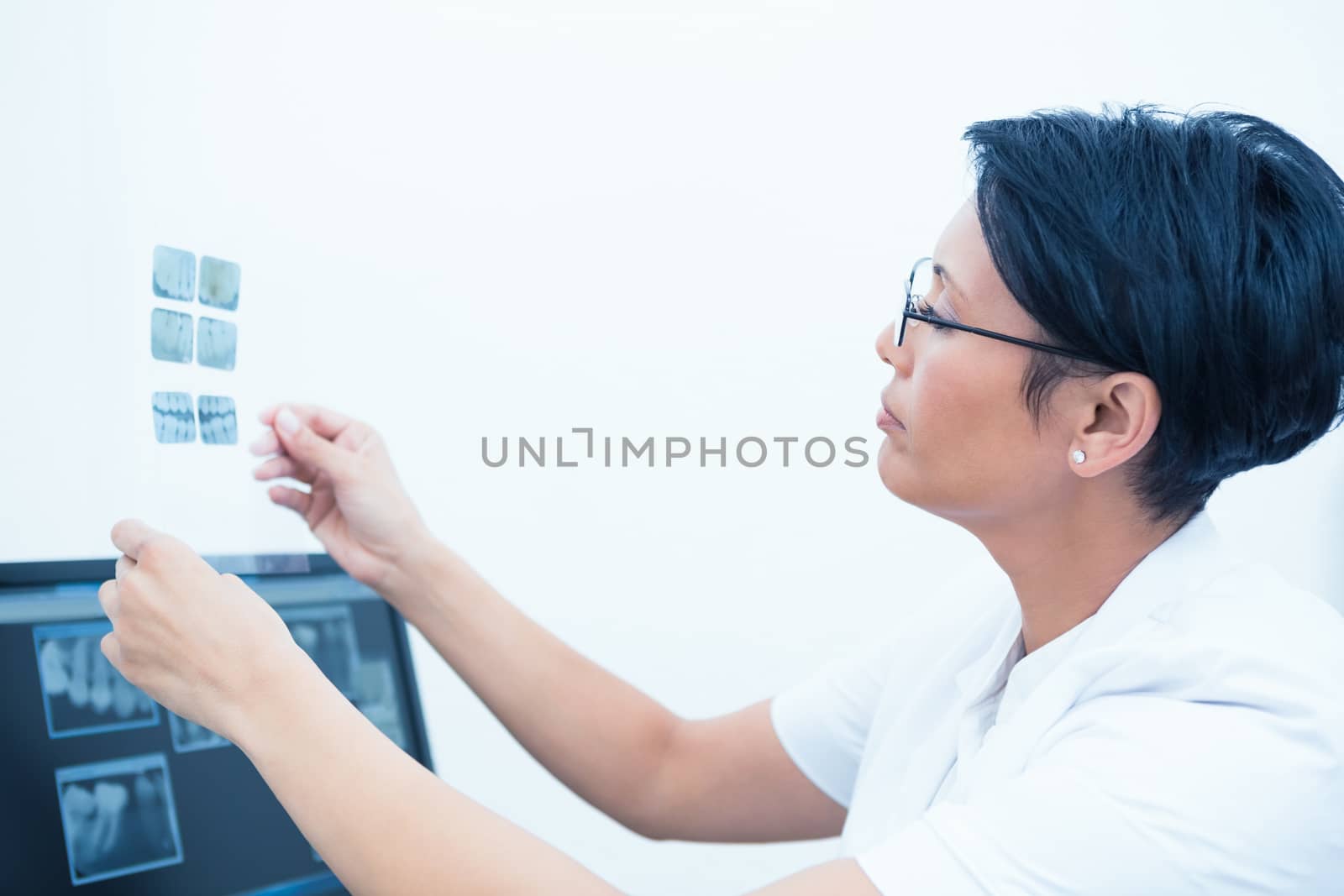 Side view of concentrated female dentist looking at x-ray