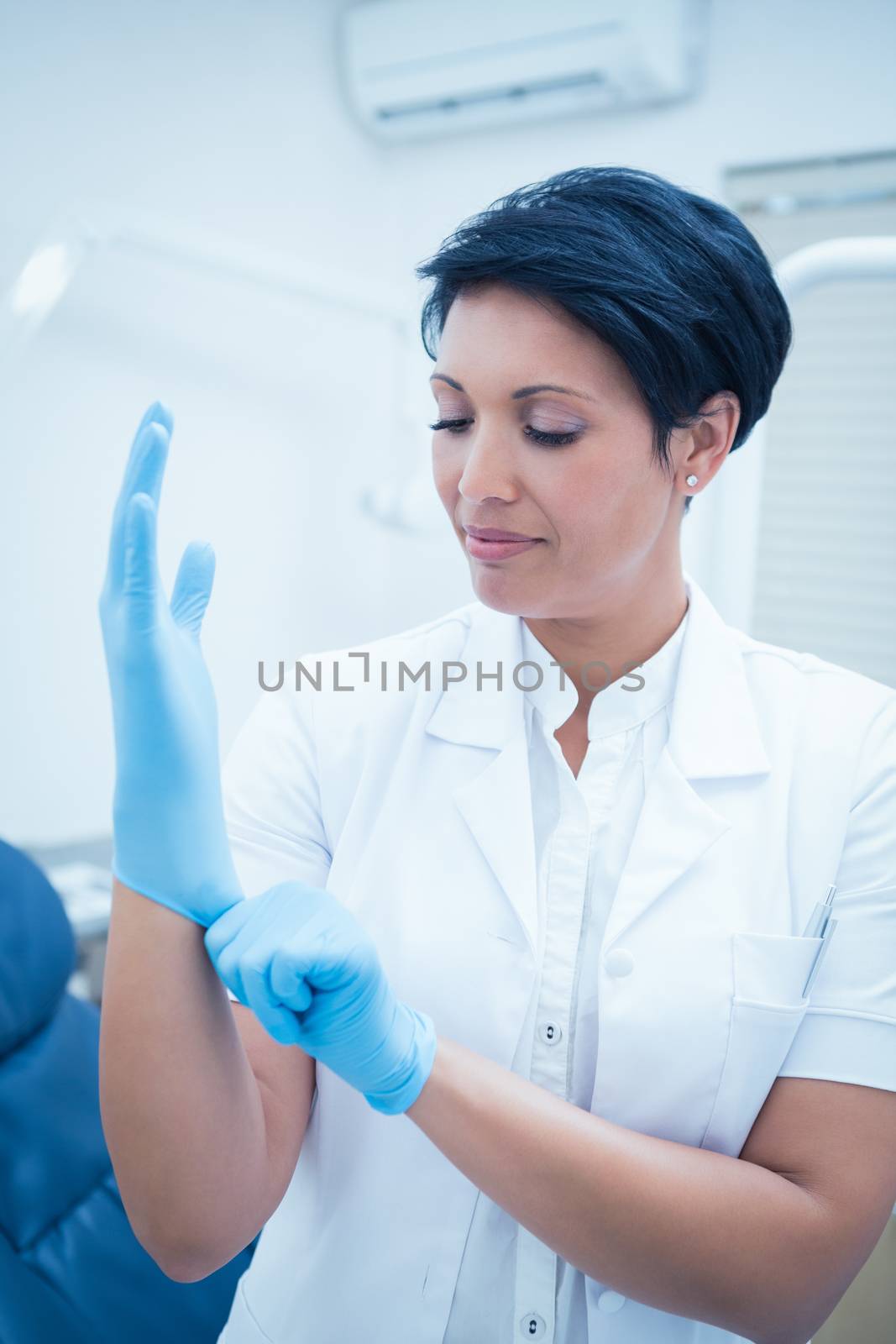 Dentist wearing surgical glove by Wavebreakmedia