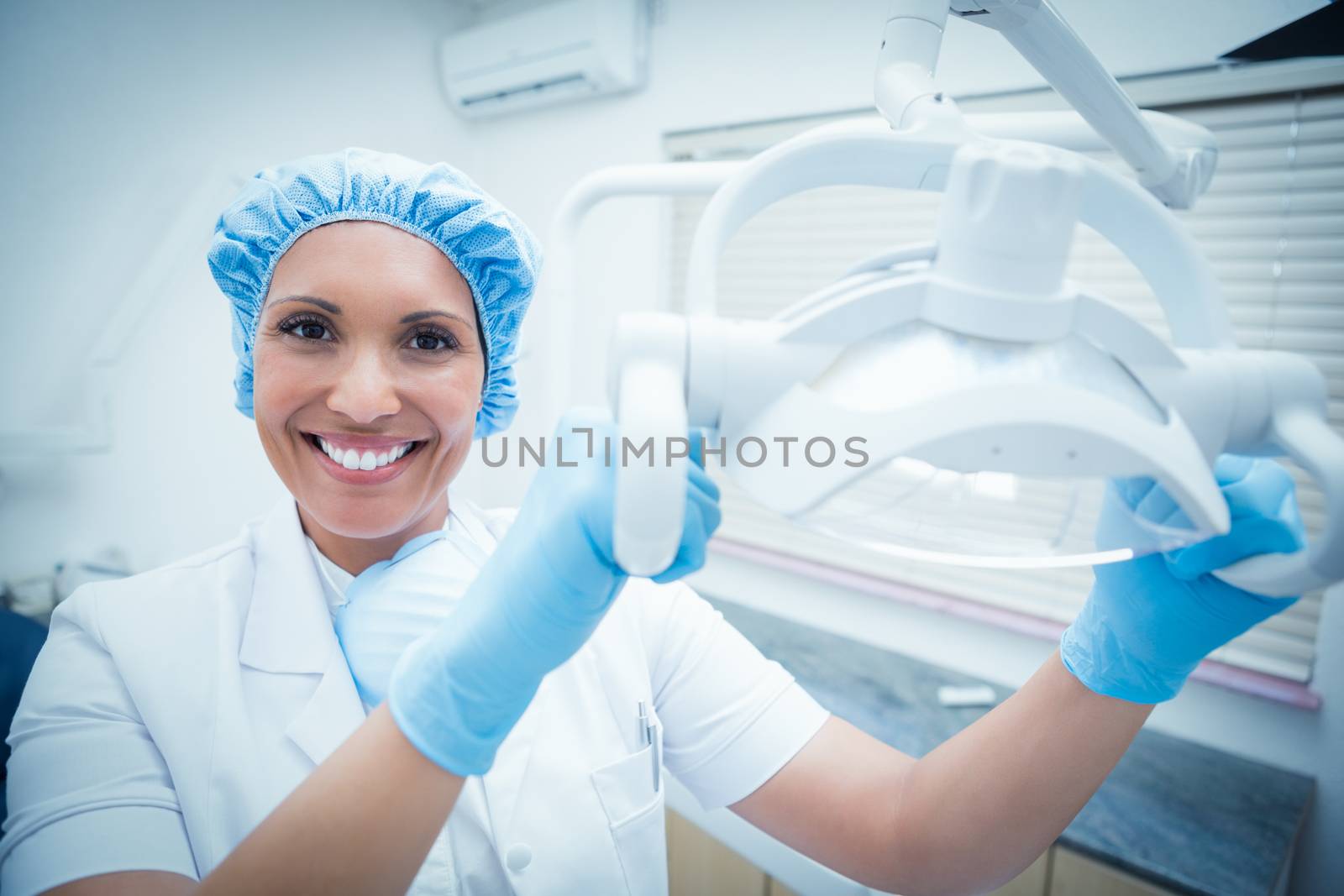 Portrait of smiling female dentist adjusting light