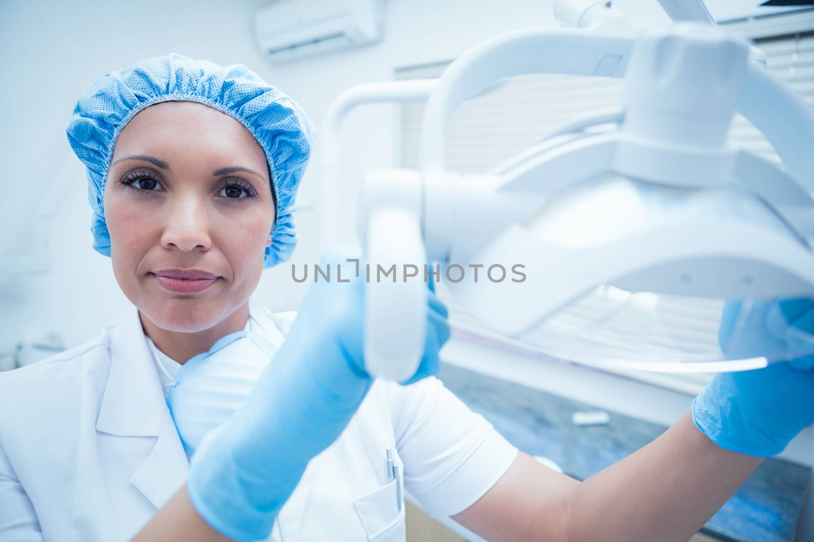 Portrait of serious female dentist adjusting light