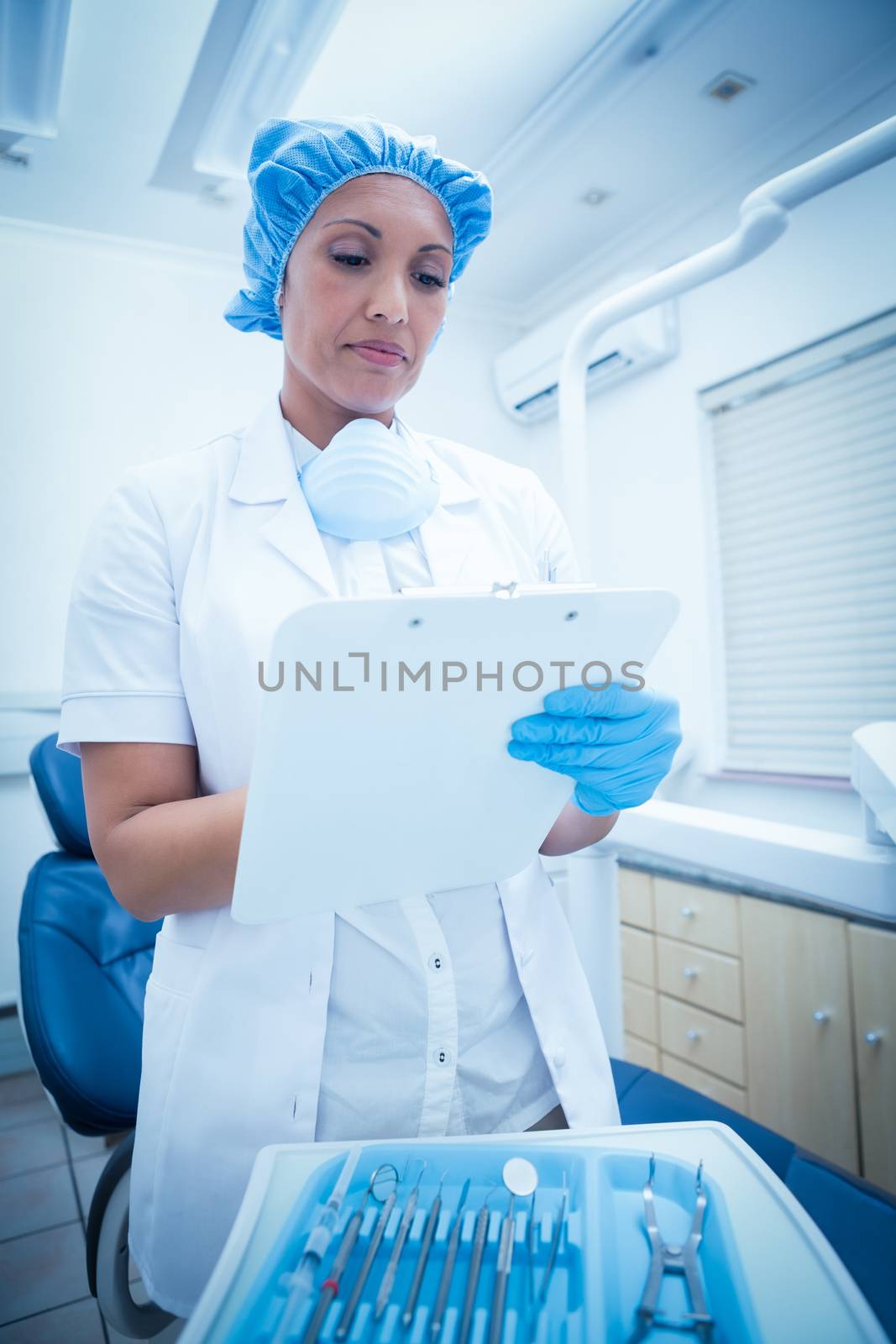 Serious female dentist checking reports