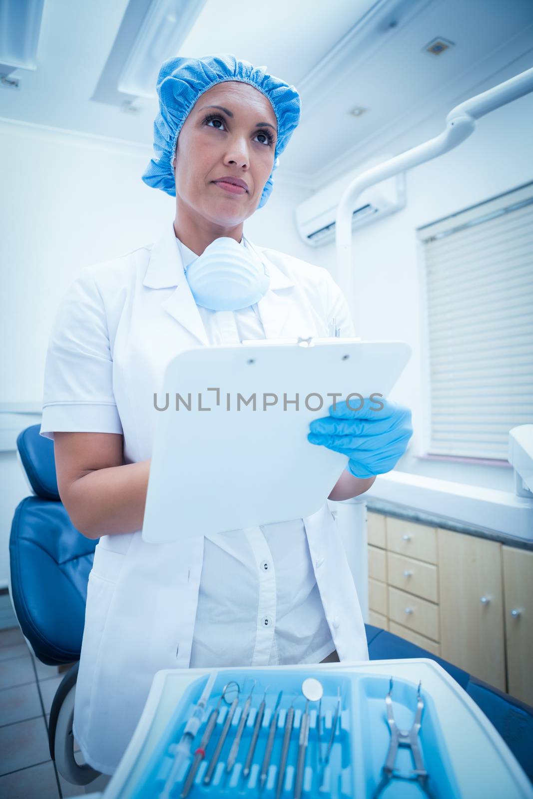 Serious female dentist checking reports