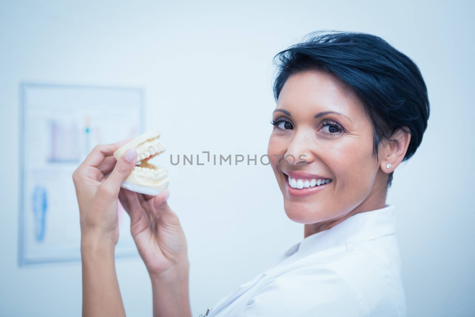 Close up portrait of smiling female dentist holding mouth model