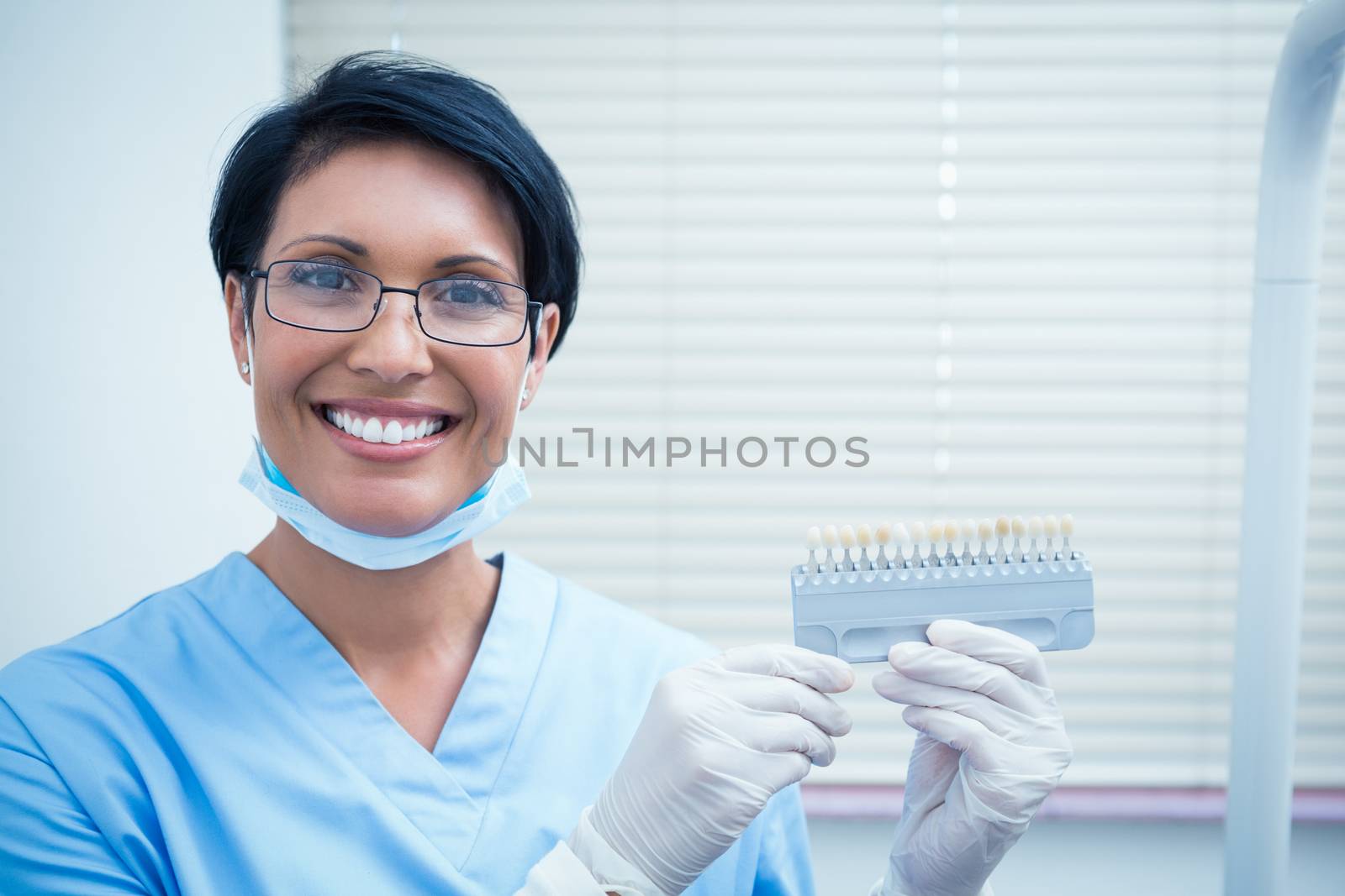 Smiling female dentist holding teeth model by Wavebreakmedia