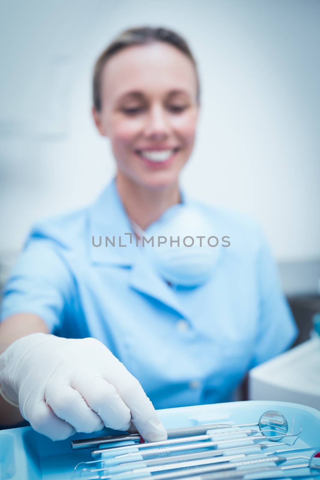 Portrait of female dentist picking dental tools