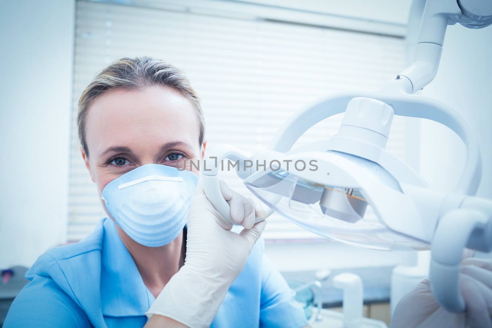 Portrait of young female dentist adjusting light