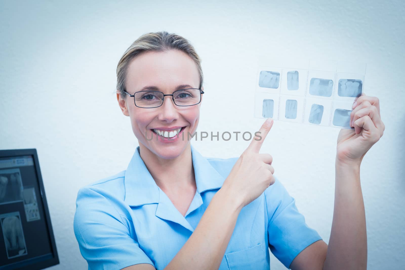 Portrait of smiling young female dentist pointing at x-ray