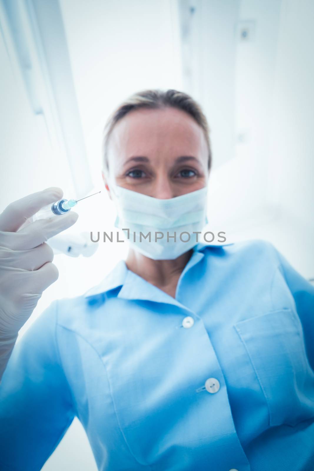 Female dentist in surgical mask holding injection by Wavebreakmedia