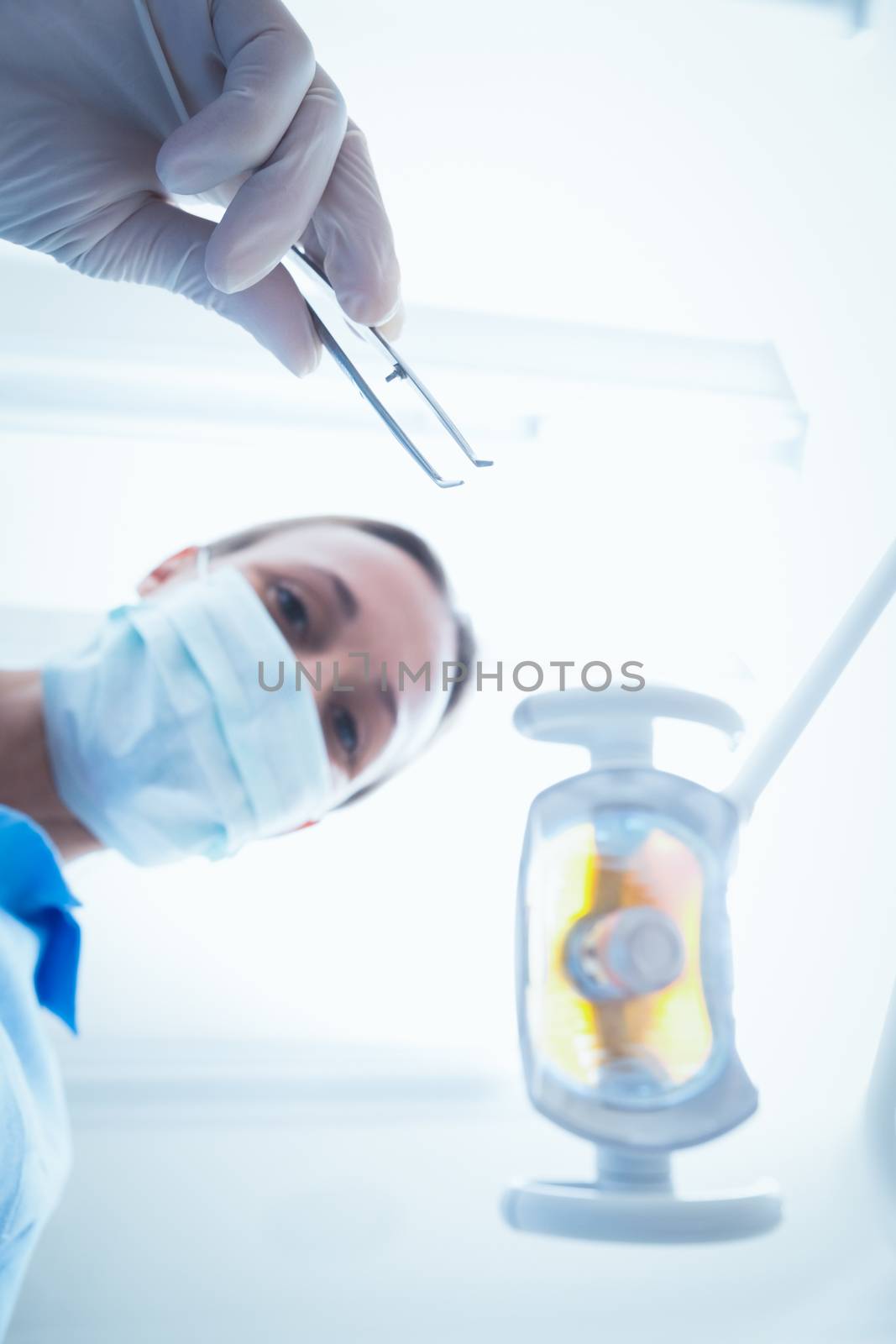 Female dentist in surgical mask holding dental tool by Wavebreakmedia