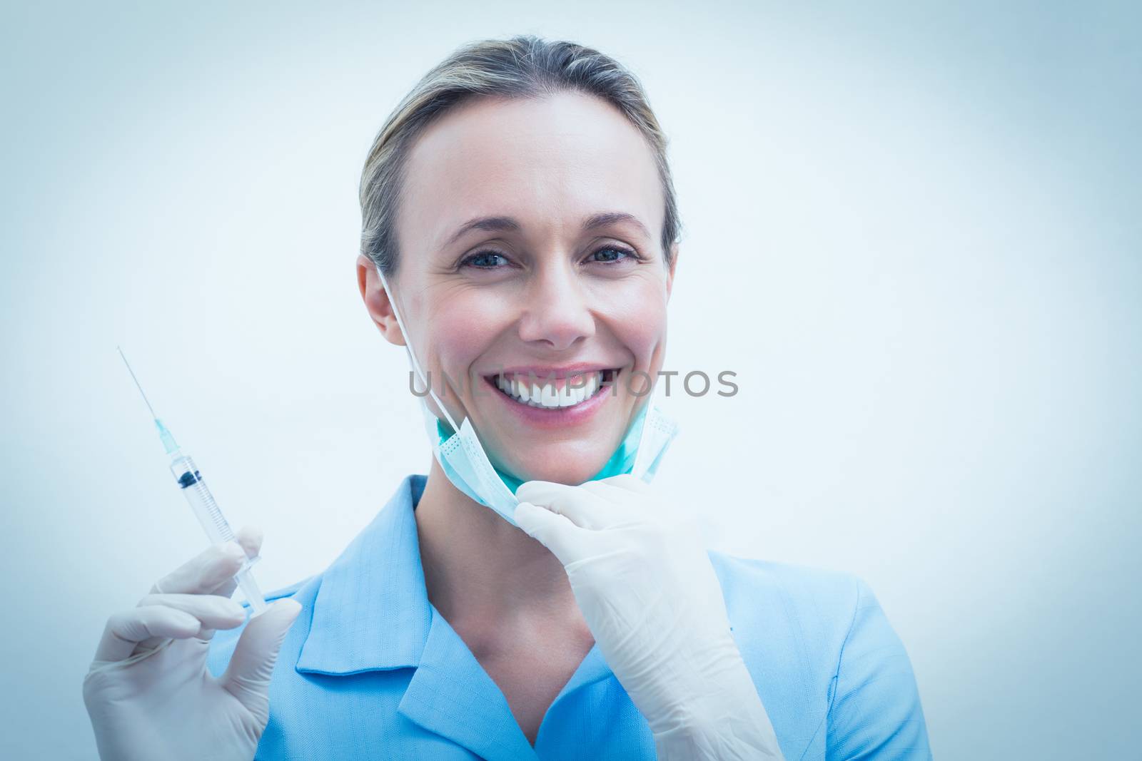 Smiling female dentist holding injection by Wavebreakmedia