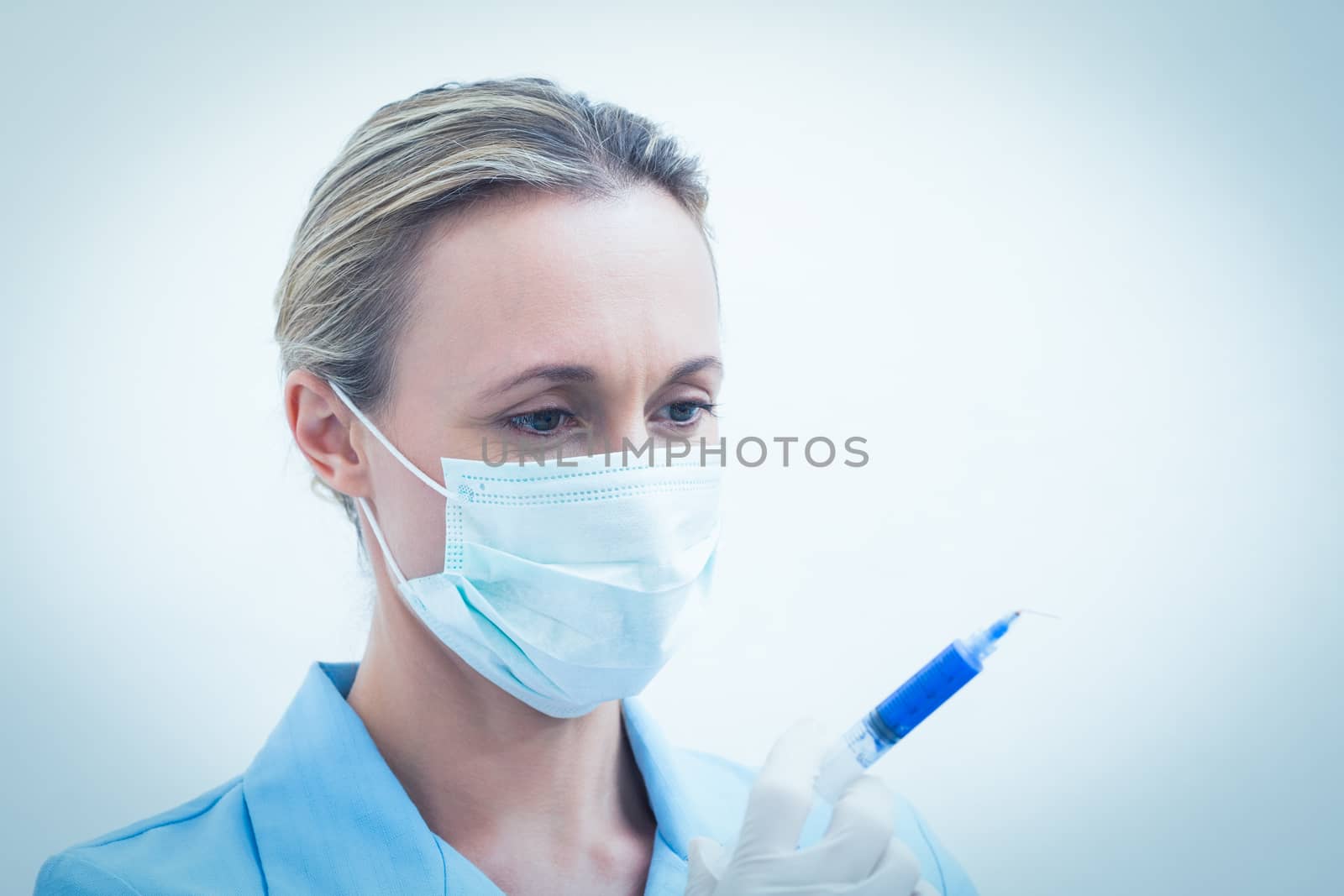 Portrait of young female dentist in surgical mask holding injection