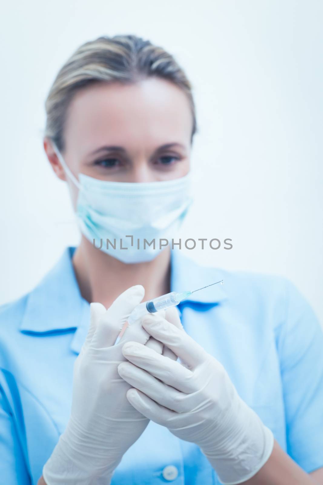 Portrait of young female dentist in surgical mask holding injection