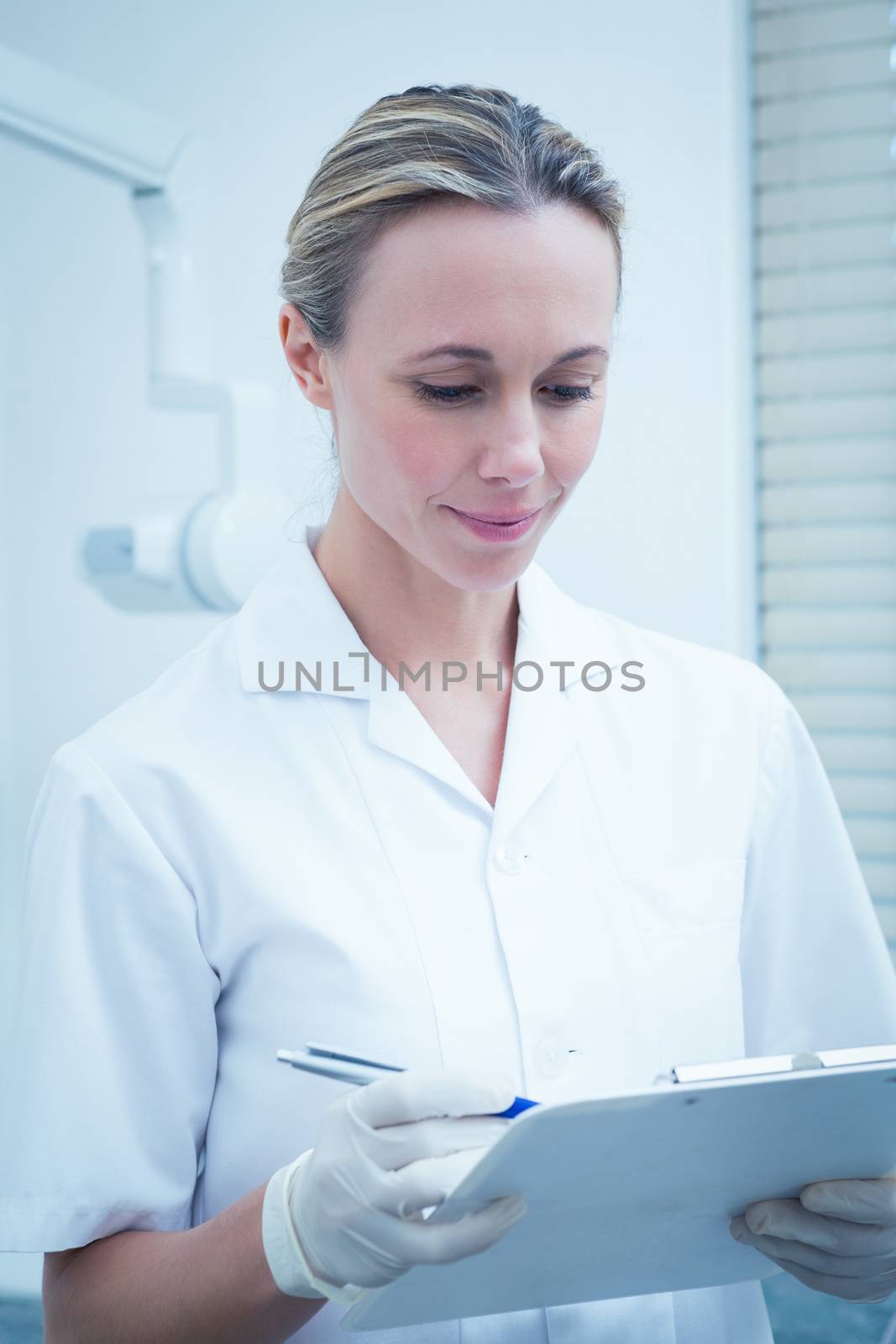 Serious young female dentist checking reports