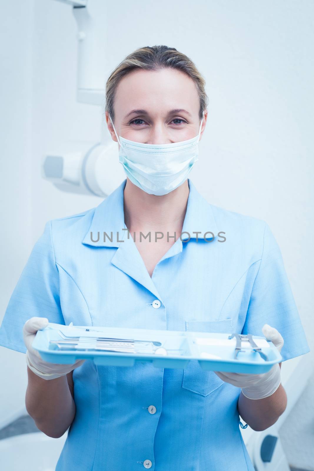 Female dentist in surgical mask holding tray of tools by Wavebreakmedia