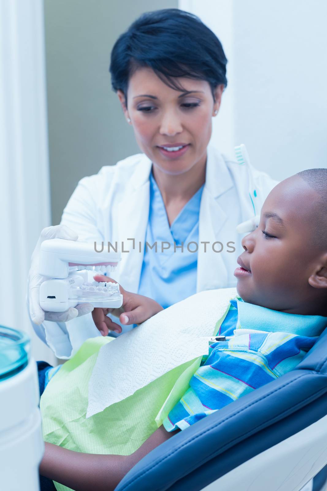 Female dentist showing young boy prosthesis teeth