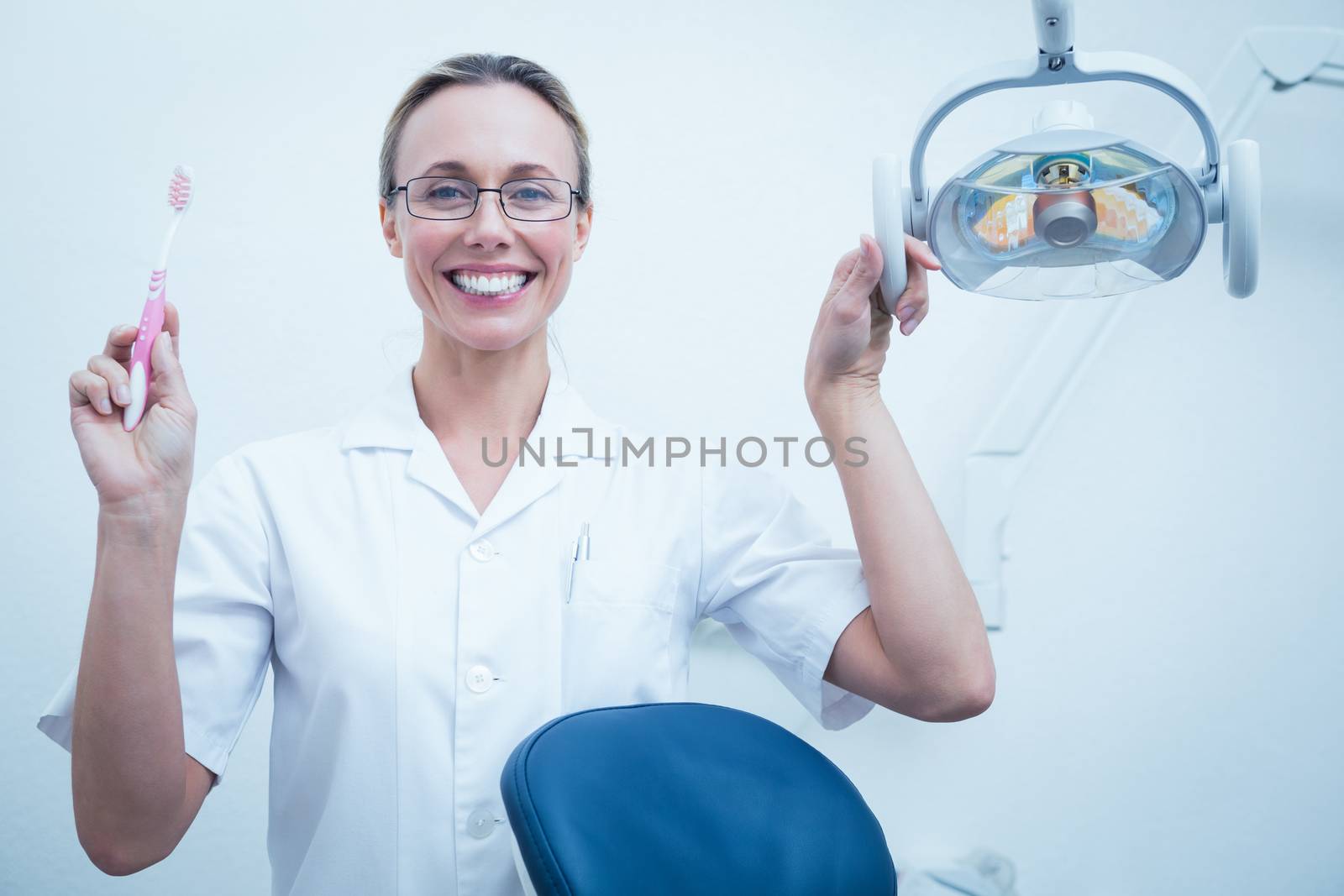 Smiling female dentist holding toothbrush by Wavebreakmedia