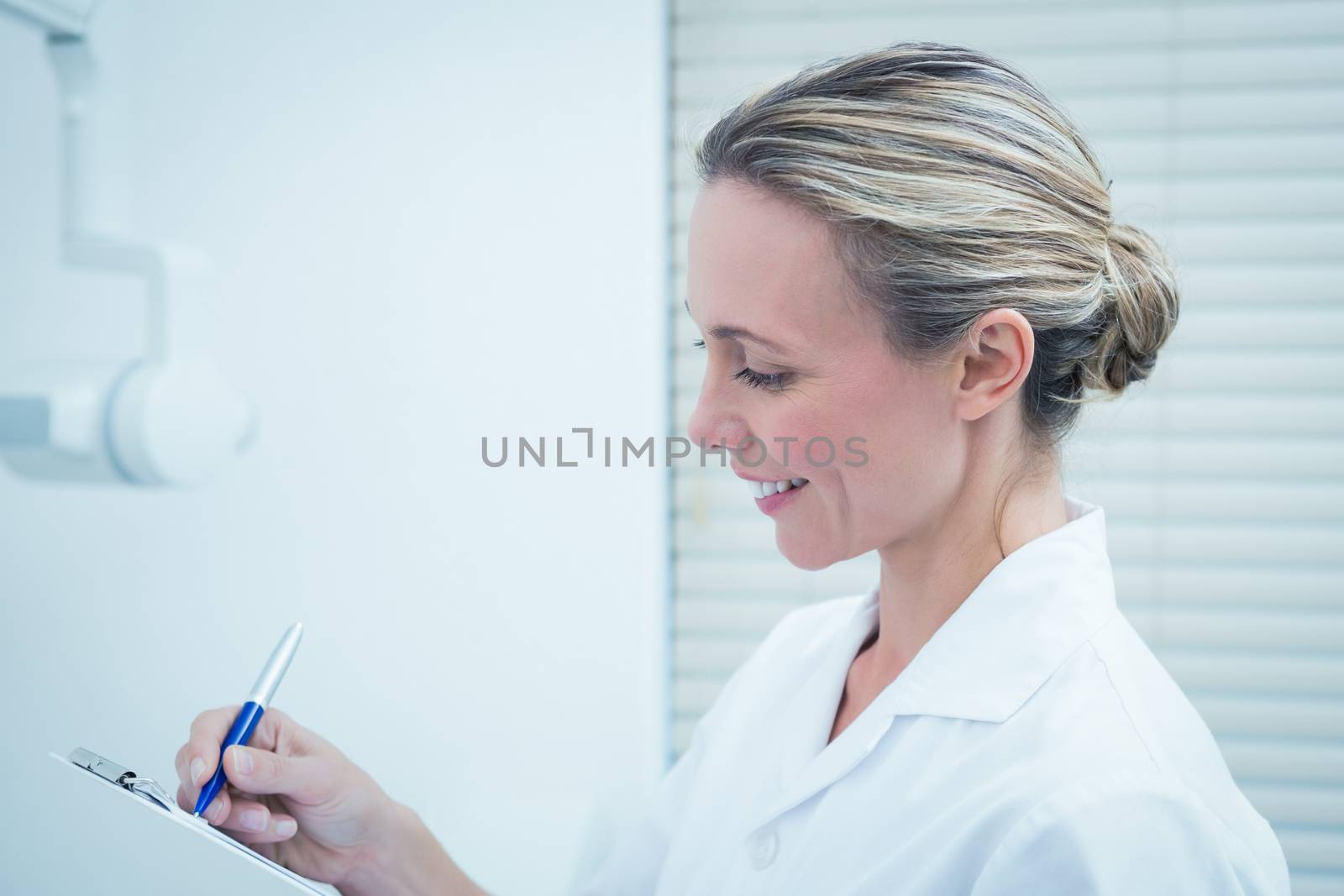 Side view of young female dentist checking reports