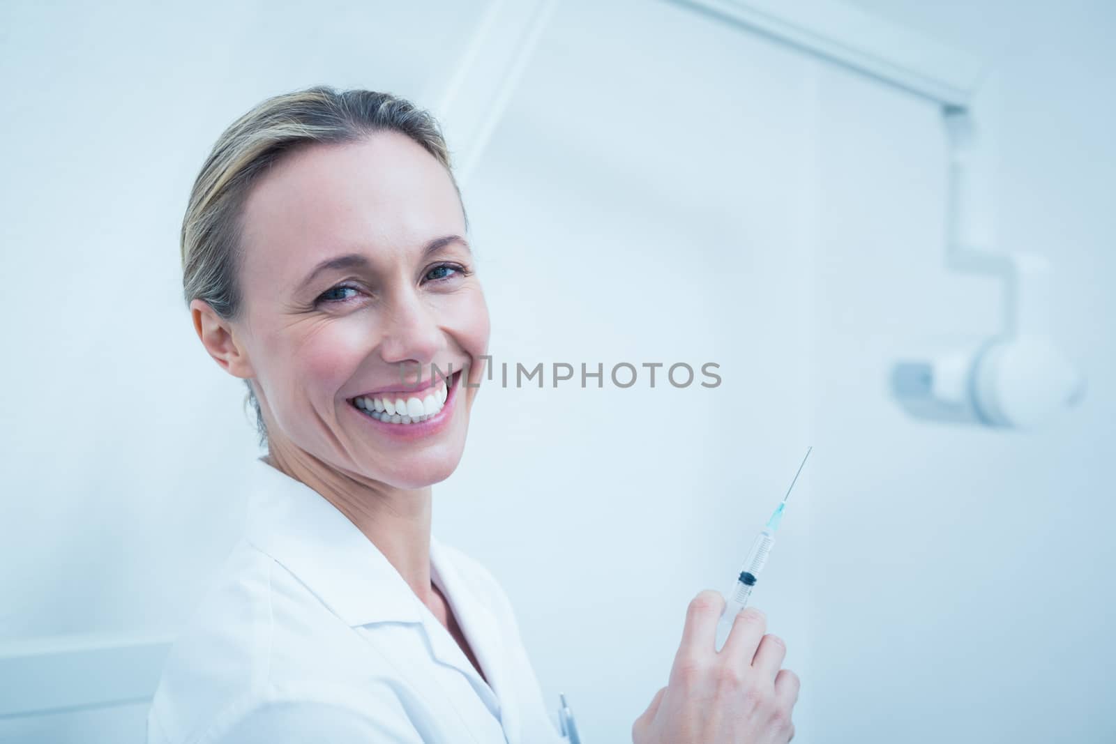 Portrait of smiling young female dentist holding injection