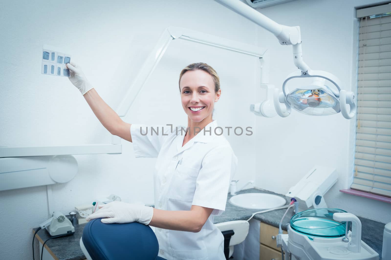 Portrait of smiling young female dentist looking at x-ray