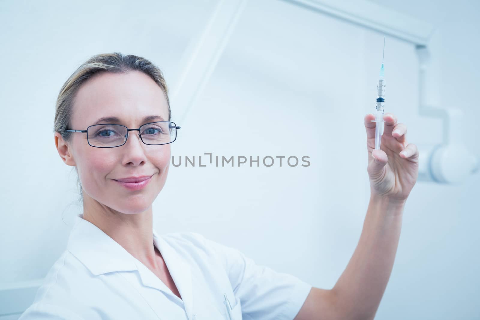 Portrait of smiling young female dentist holding injection