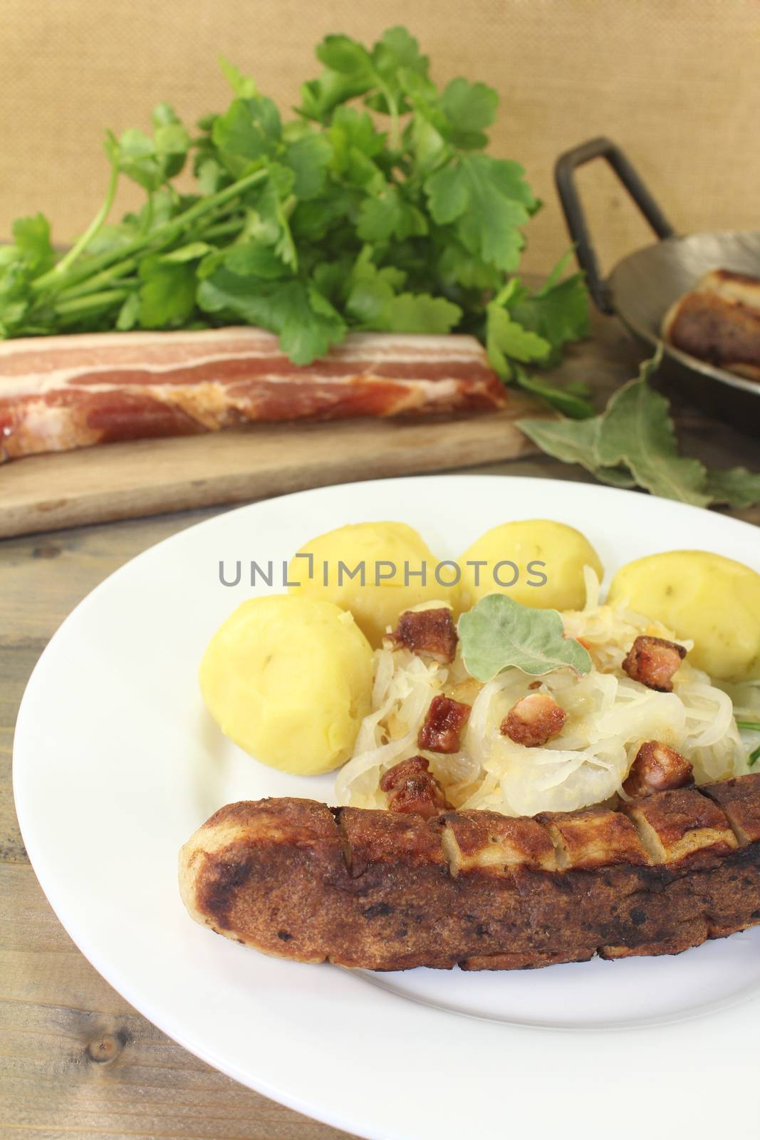 Brawurst with sauerkraut and bacon on a wooden plate