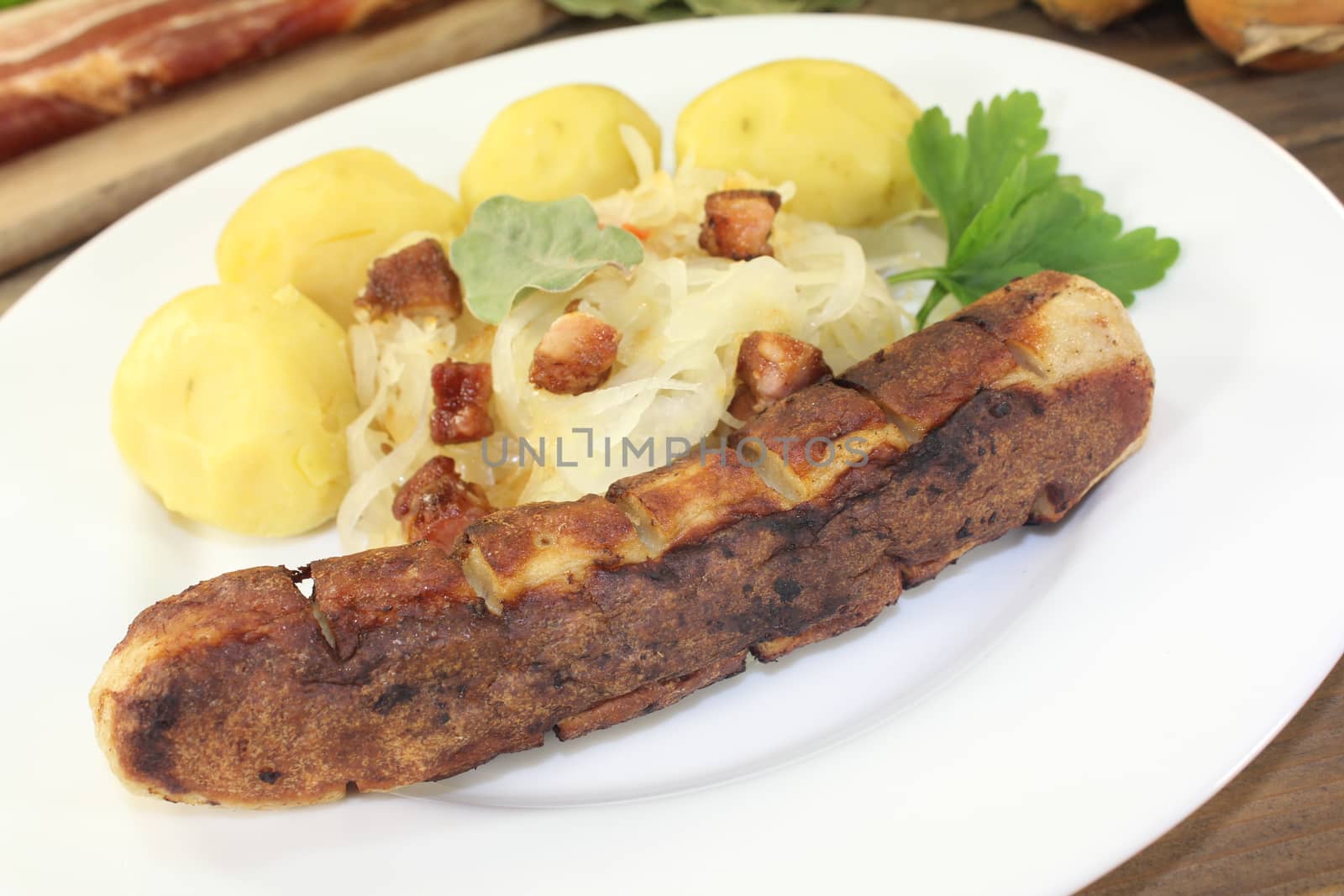 Brawurst and sauerkraut with bacon and laurel on a wooden plate