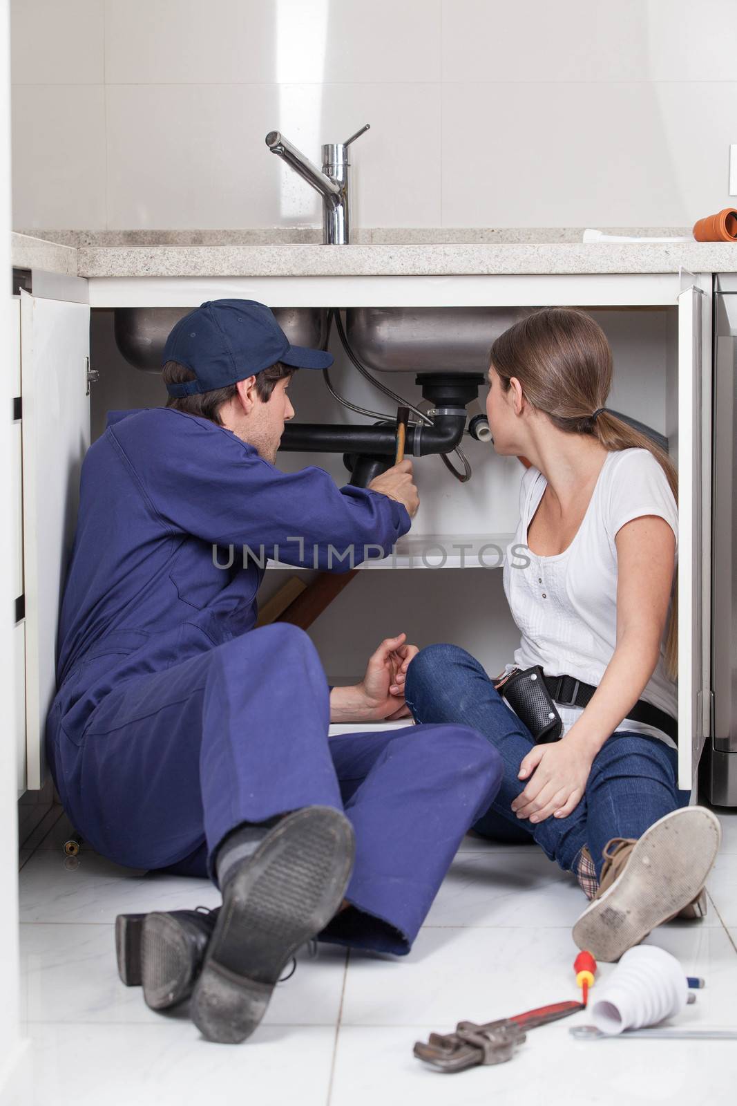 Pair of plumbers fixing the pipe of the kitchen