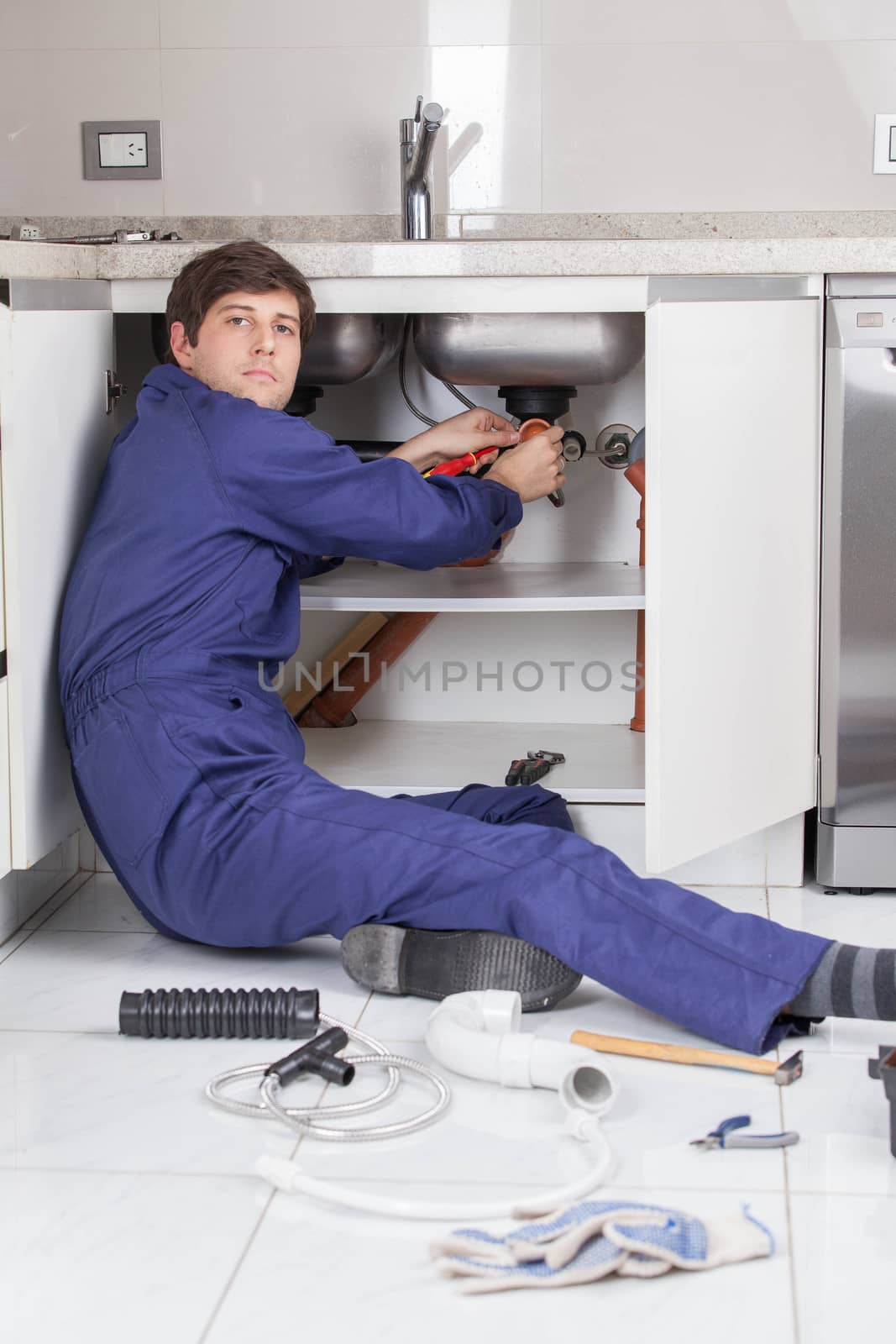 Plumber sitting on the floor repair a pipe