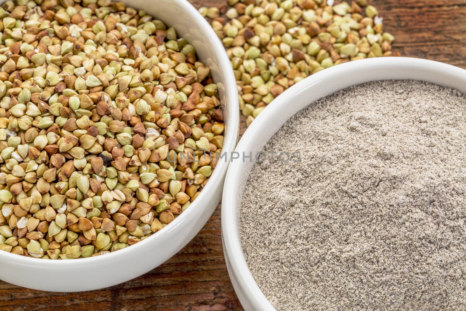 gluten free buckwheat grain and flour - top view of two ceramic bowls against rustic wood