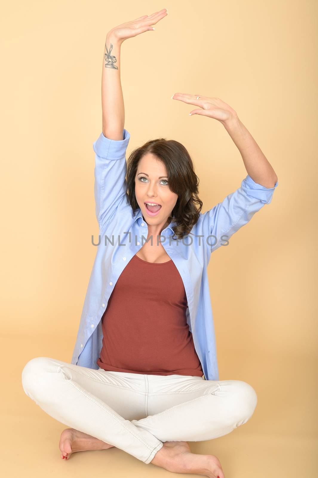 Attractive Young Woman Sitting on the Floor Wearing a Blue Shirt and White Jeans Stretching and Yawning