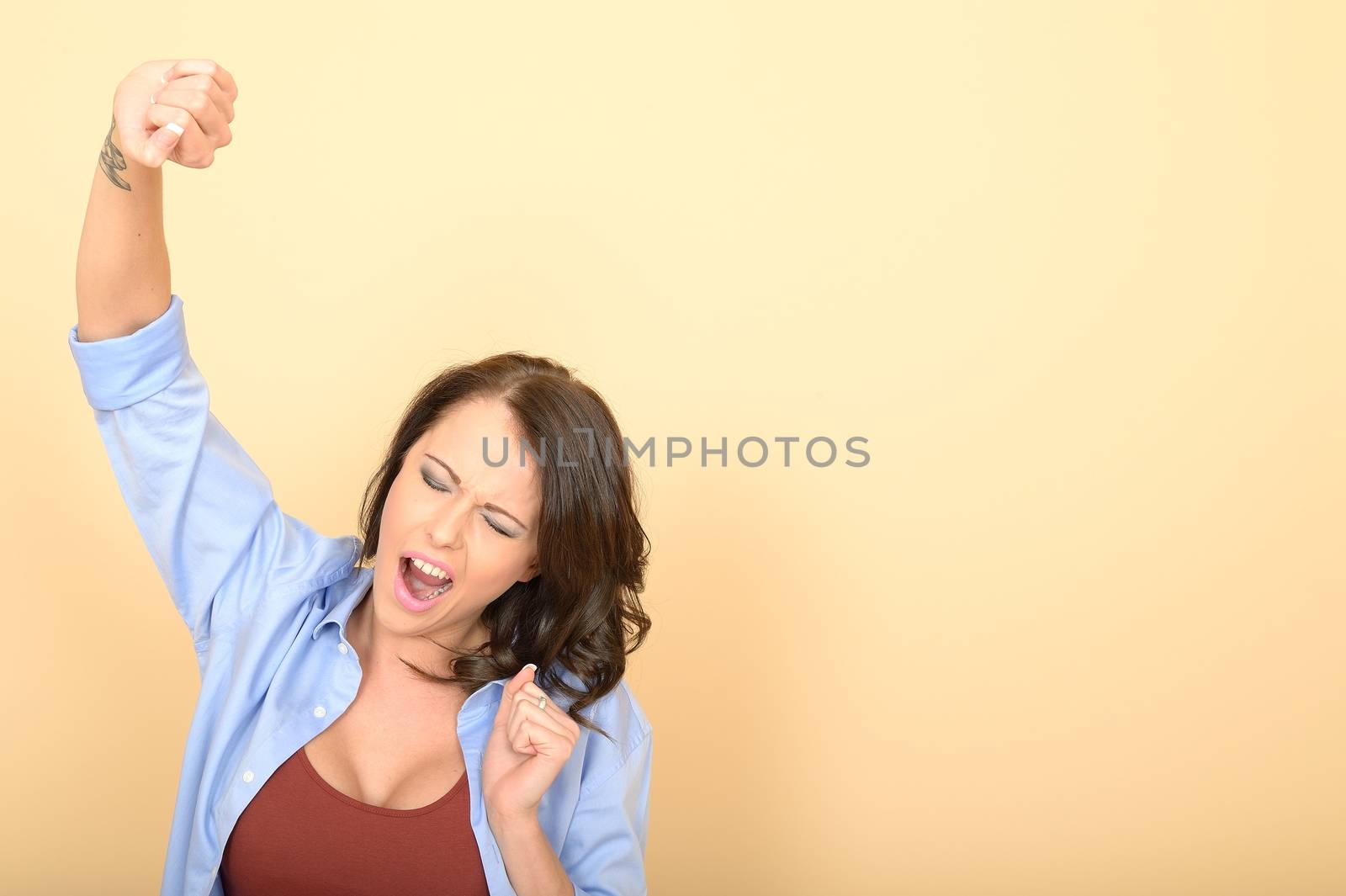 Attractive Young Woman Sitting on the Floor Wearing a Blue Shirt and White Jeans Stretching and Yawning