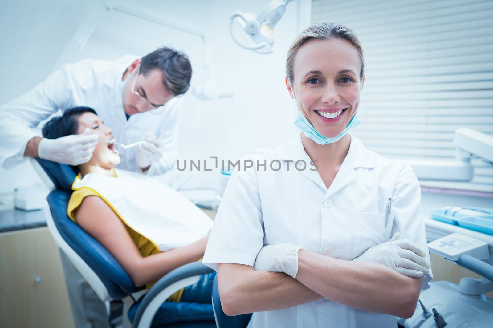Smiling female dentist with assistant examining womans teeth by Wavebreakmedia